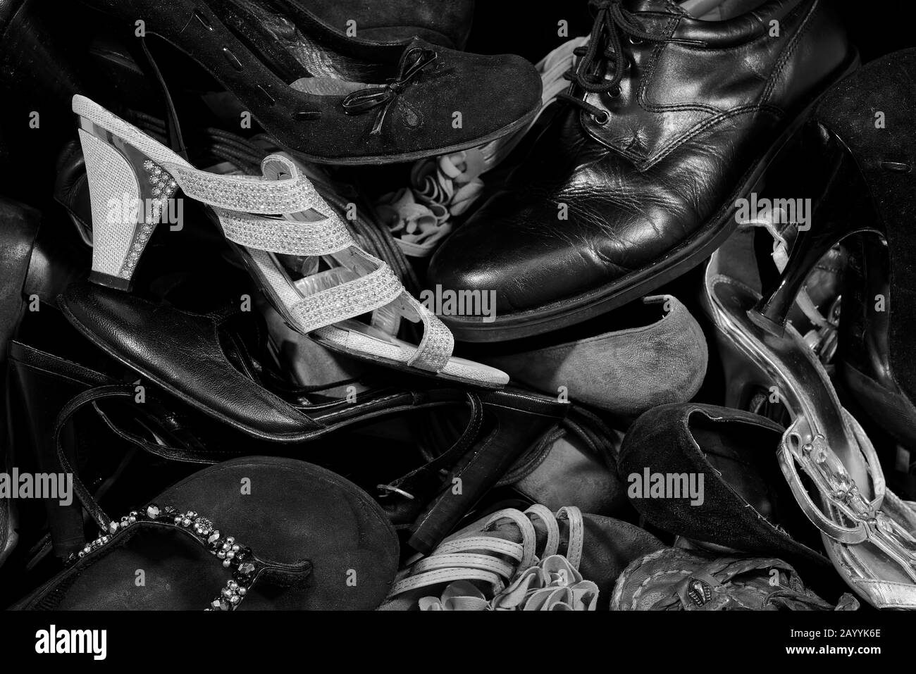 Una scarpa da uomo in un mazzo di scarpe da donna Foto Stock