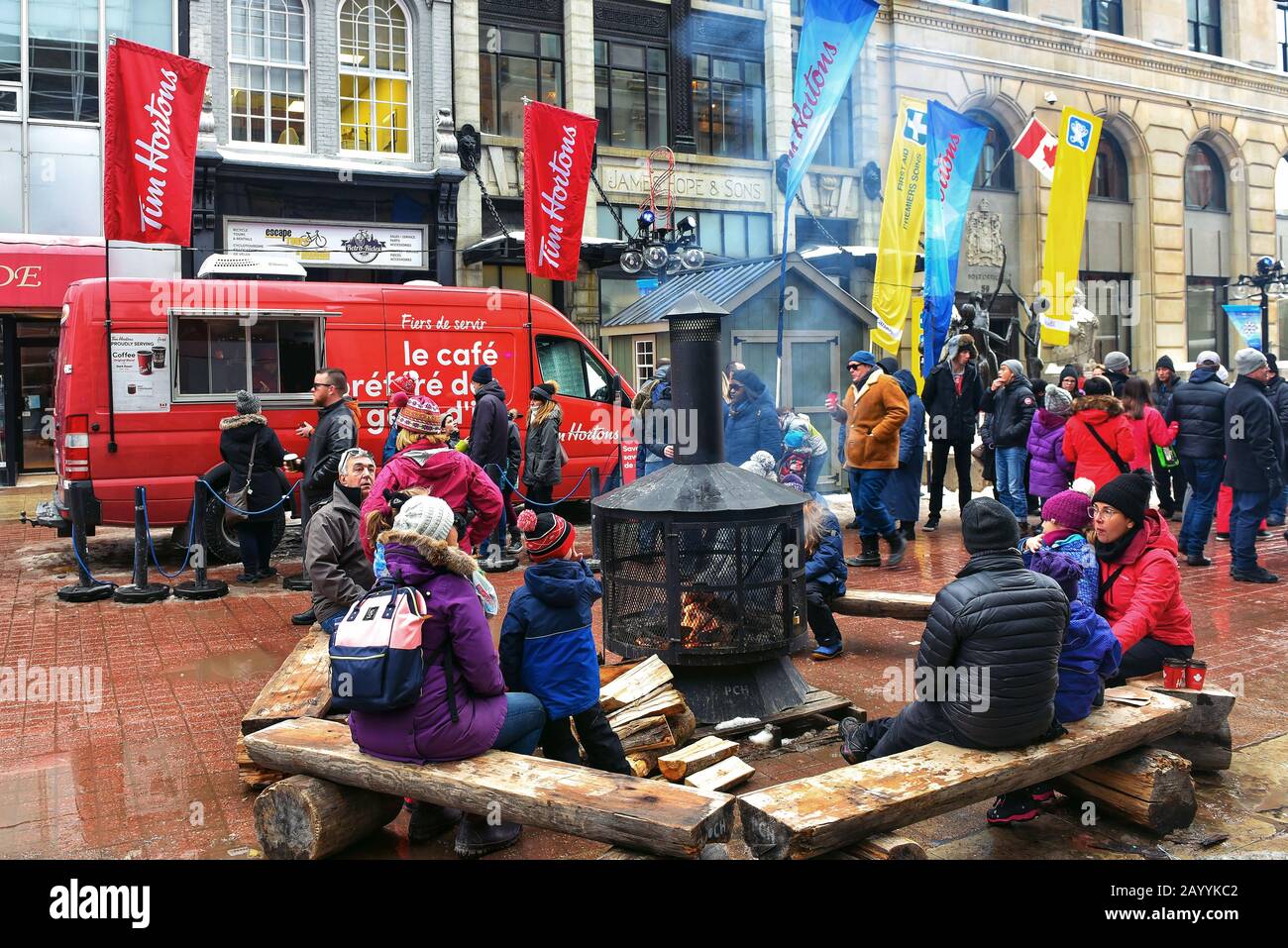 Ottawa, Canada - 16 febbraio 2020: Le persone si siedono accanto al caminetto a legna fornito per il festival Winterlude vicino al furgone di Tim Horton su Sparks Street. Foto Stock