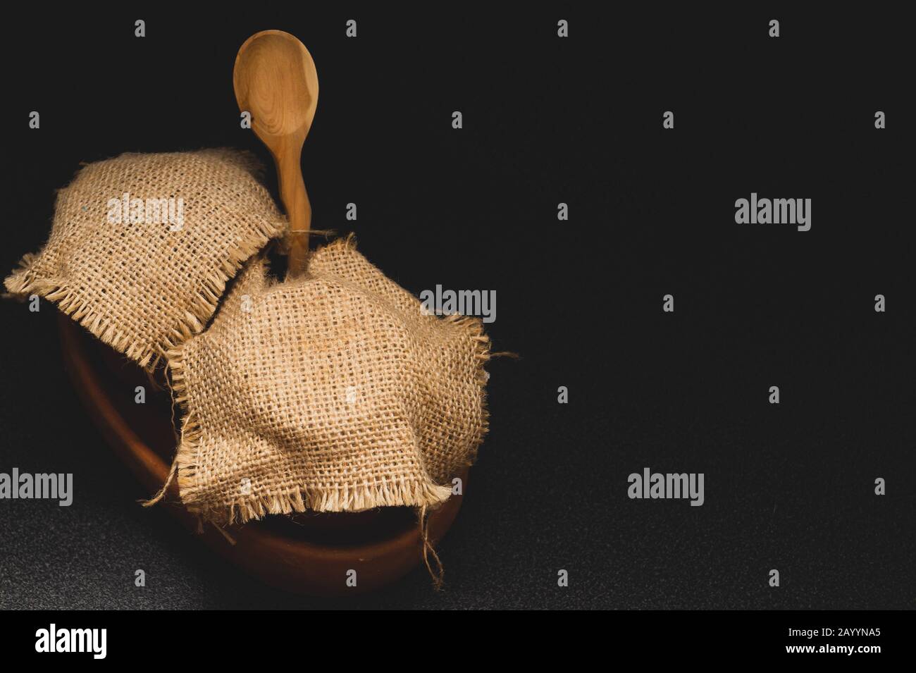 Vasi di miele con tela di lino con cucchiaio di legno su sfondo scuro Foto Stock