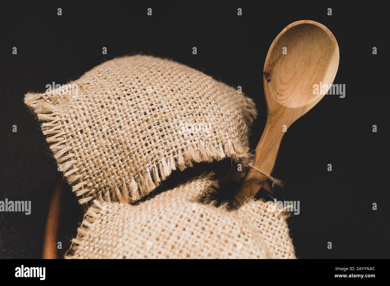 Vasi di miele con tela di lino con cucchiaio di legno su sfondo scuro Foto Stock