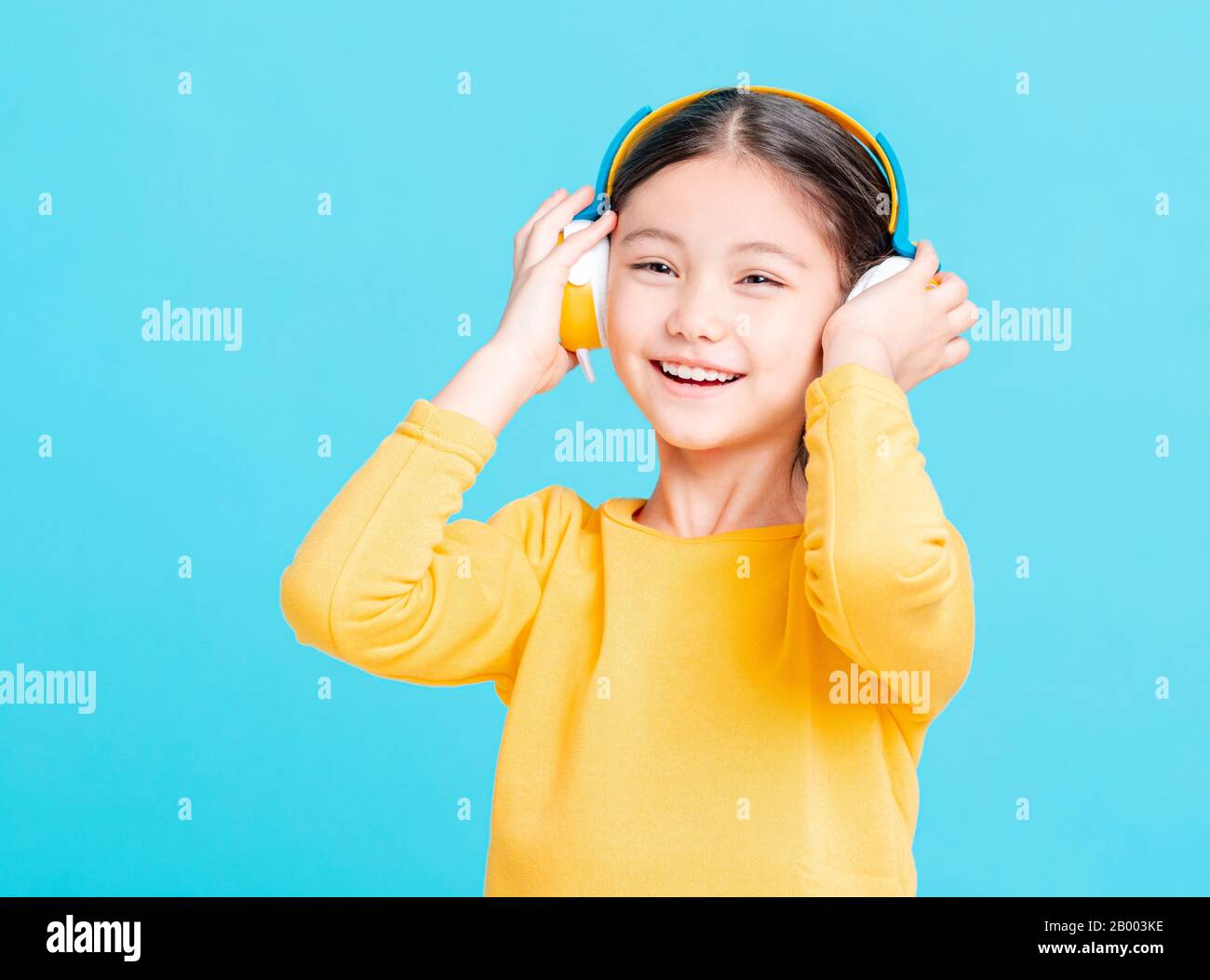 La bambina felice ascolta la musica in cuffia Foto Stock