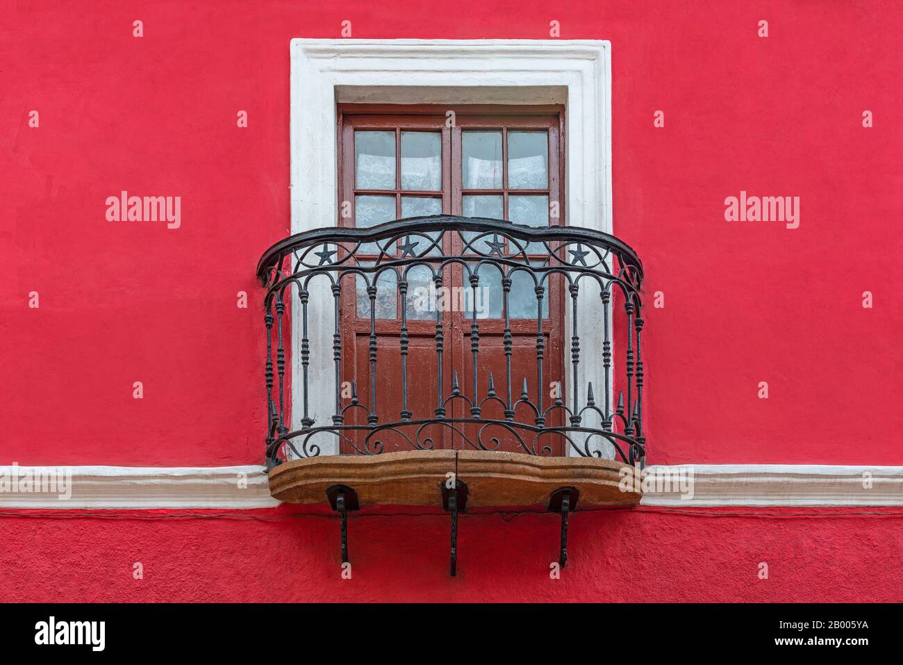 Balcone in stile coloniale con finestra in legno, decorazioni in ferro battuto e facciata rossa, Potosi, Bolivia. Foto Stock