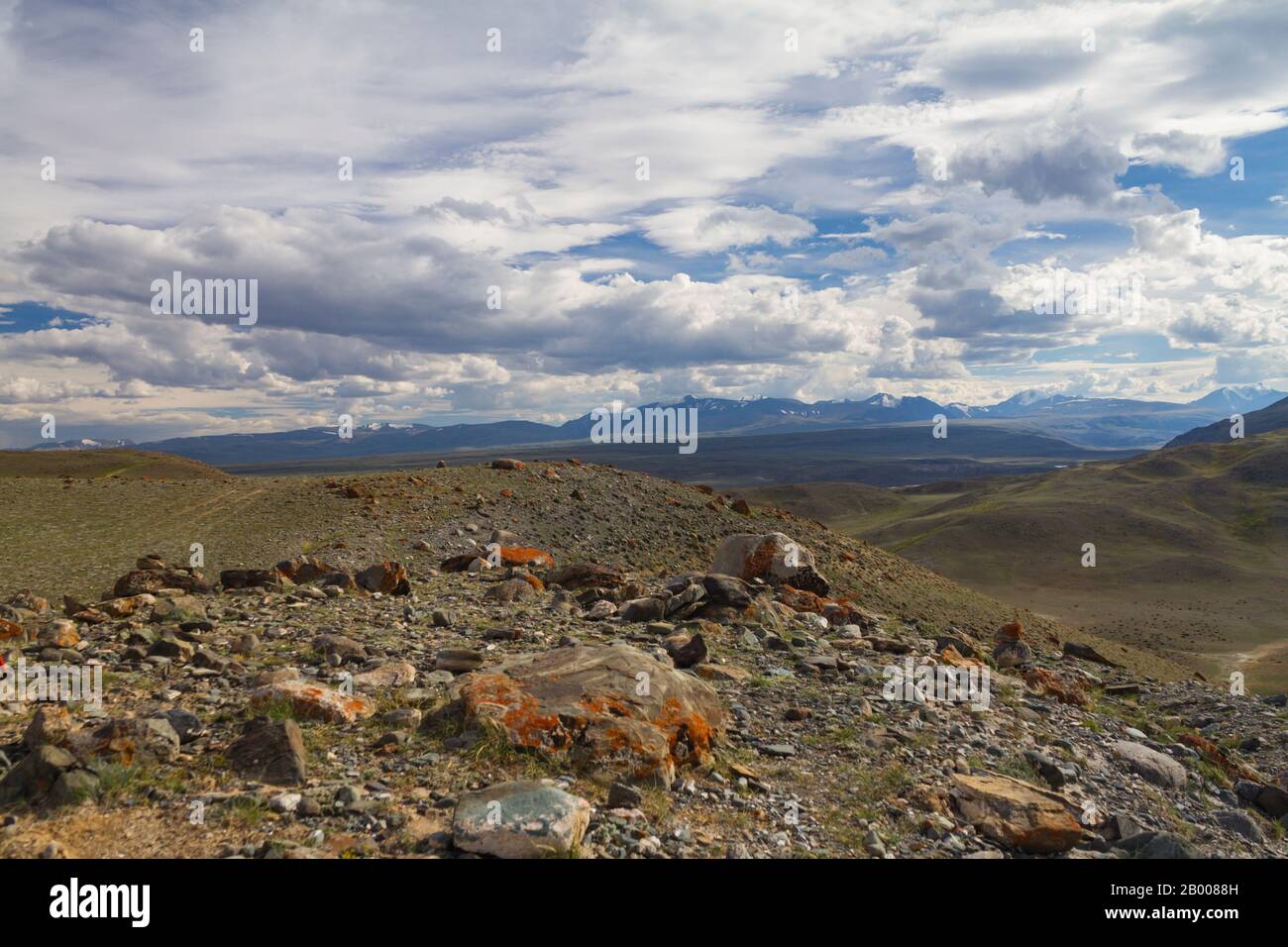 Vista panoramica di una valle di montagna estate, luce soffusa, nuvole bianche, cielo blu. Montagne Altai. Grandi rocce nella vista frontale. Foto Stock
