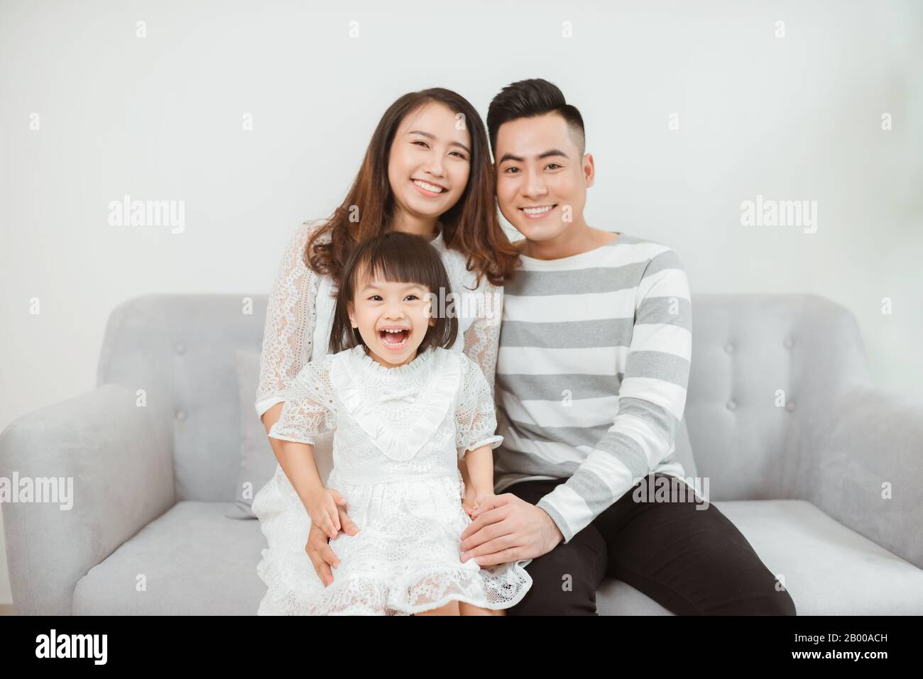 Felice giovane famiglia seduta sul divano e godere di un buon tempo insieme Foto Stock