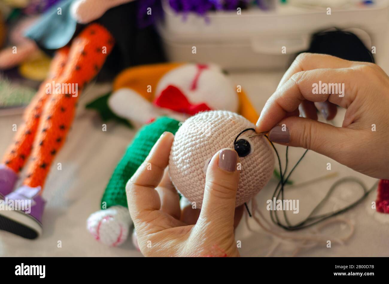 Fare coniglio a crochet colorato. Il giocattolo per bambini o trinket. Sui fili del tavolo, aghi, gancio, filo di cotone. Regalo fatto a mano. Foto Stock