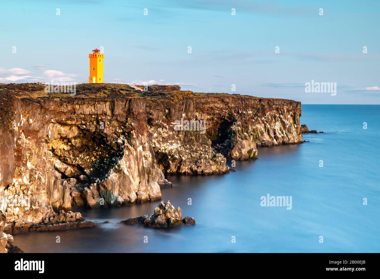 Faro arancione di Oendverdarnes sorge sulla costa della scogliera, costa rocciosa di roccia lavica, esposizione a lungo termine, Oendveroarnes, Snaefellsjoekull National Foto Stock