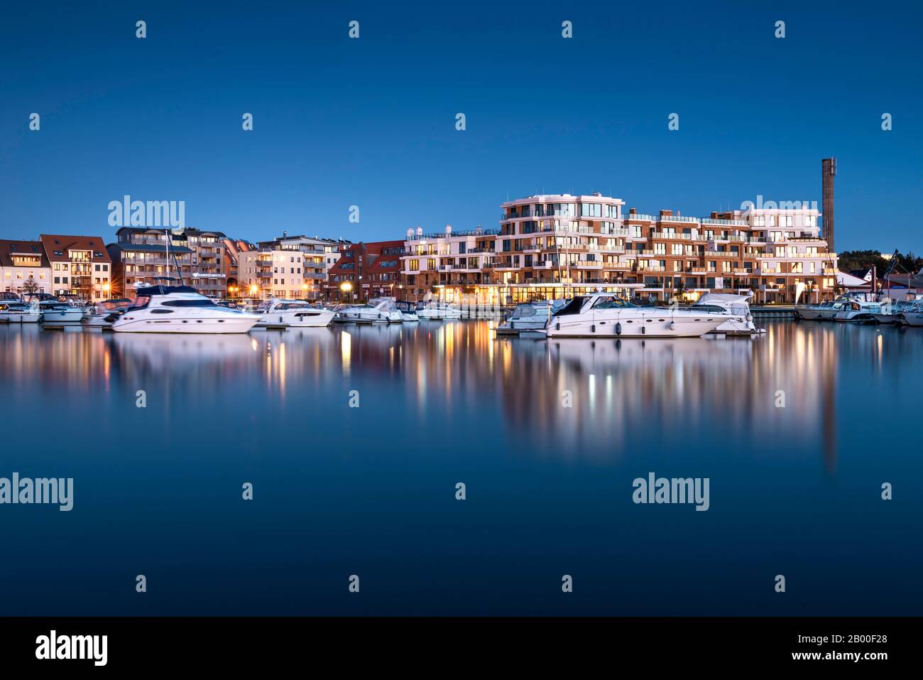 Porto cittadino con moderno complesso alberghiero al crepuscolo, Waren sul Mueritz, Mecklenburg Lake District, Mecklenburg-Pomerania Occidentale, Germania Foto Stock