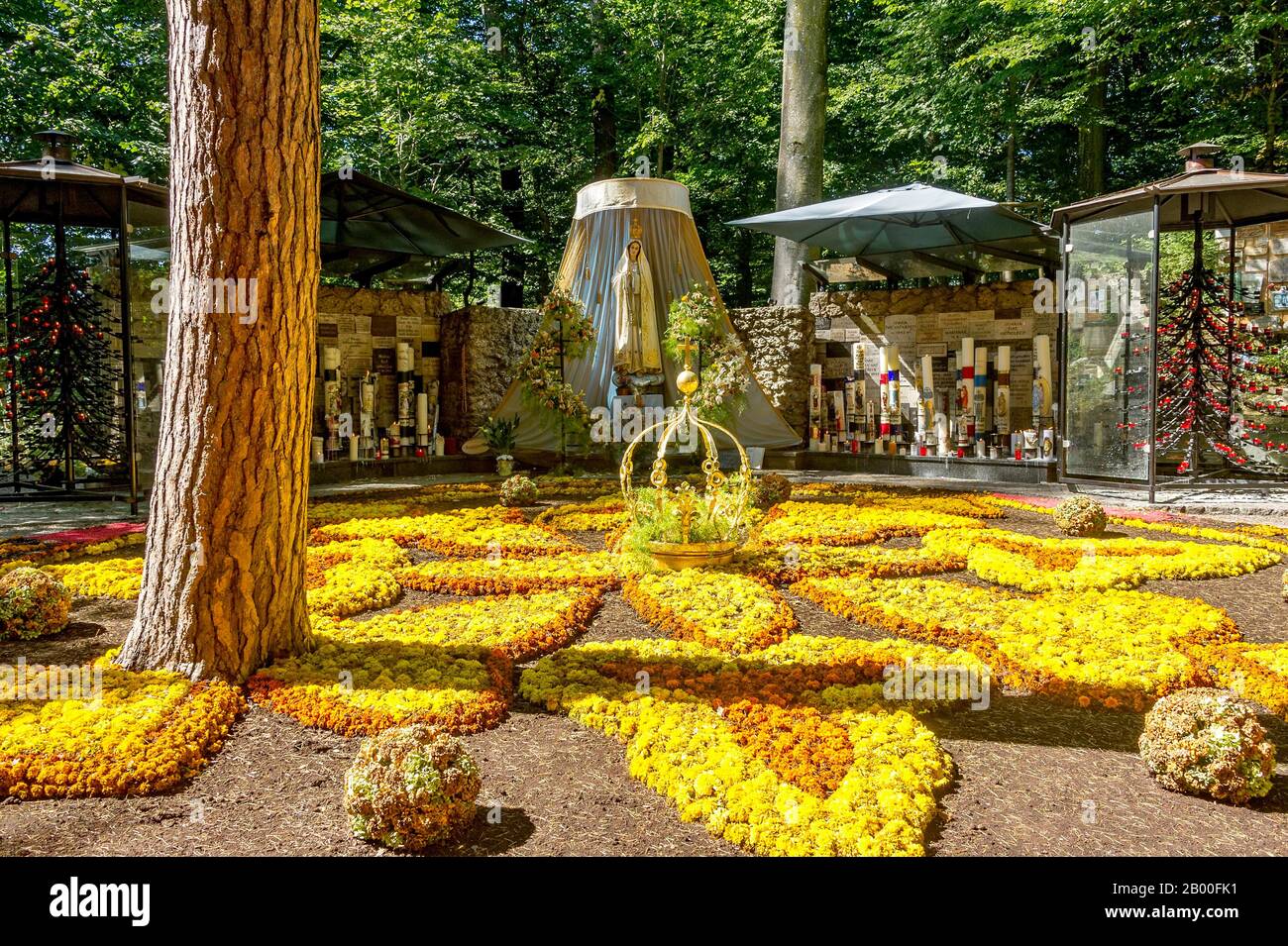 Statua della Madonna, tappeto di fiori con corona dorata della Vergine Maria, grotta della Vergine Maria nella foresta, pellegrinaggio luogo Maria Foto Stock