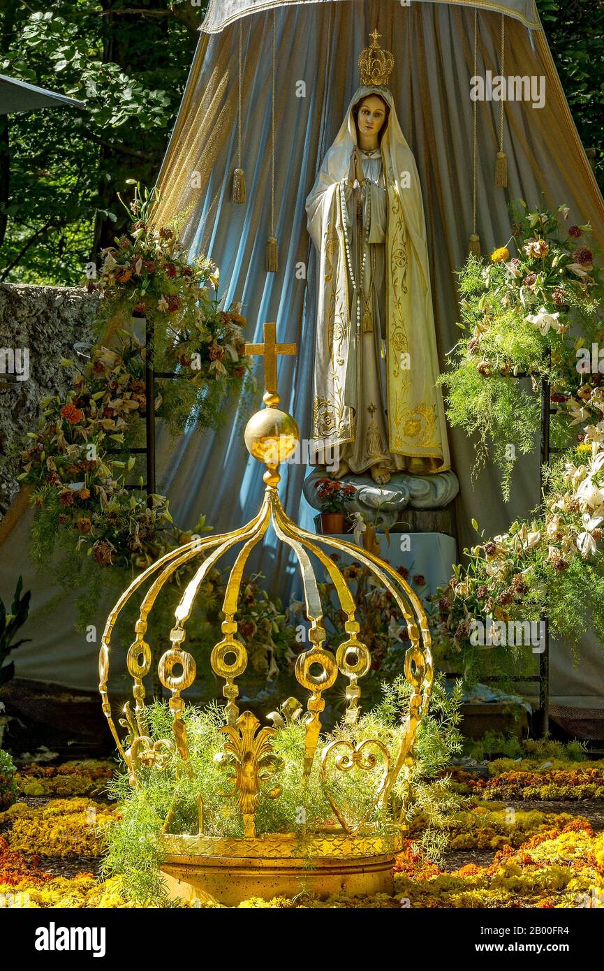 Statua della Madonna, tappeto di fiori con corona dorata della Vergine Maria, grotta della Vergine Maria nella foresta, pellegrinaggio luogo Maria Foto Stock