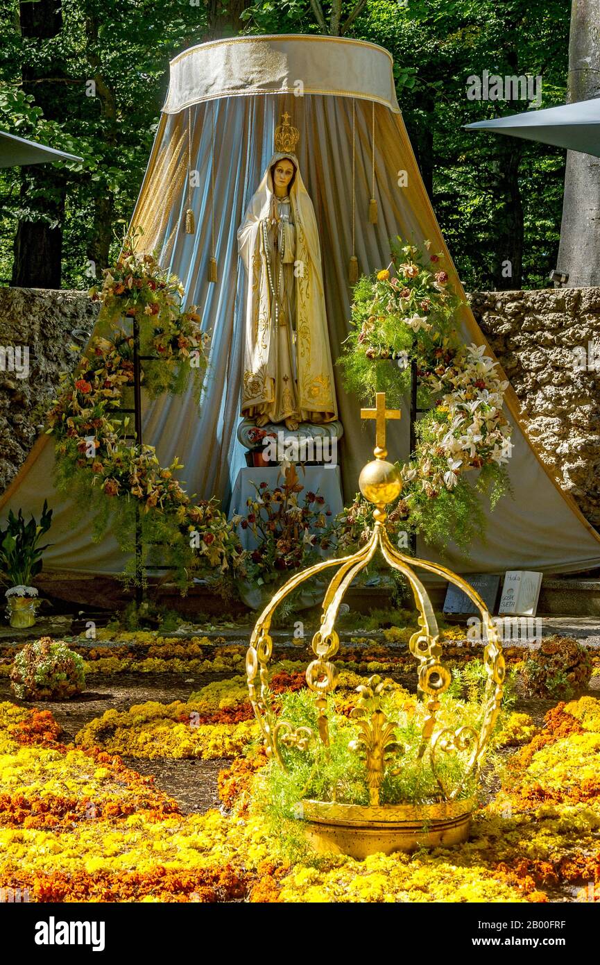 Statua della Madonna, tappeto di fiori con corona dorata della Vergine Maria, grotta della Vergine Maria nella foresta, pellegrinaggio luogo Maria Foto Stock