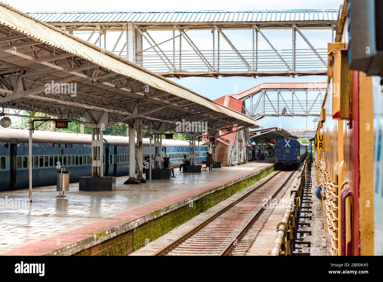 Pendolari giornalieri e treni arrestati in attesa del segnale di partenza alla piattaforma pulita e meno affollata delle ferrovie indiane. Ponte pedonale per l'attraversamento. Foto Stock