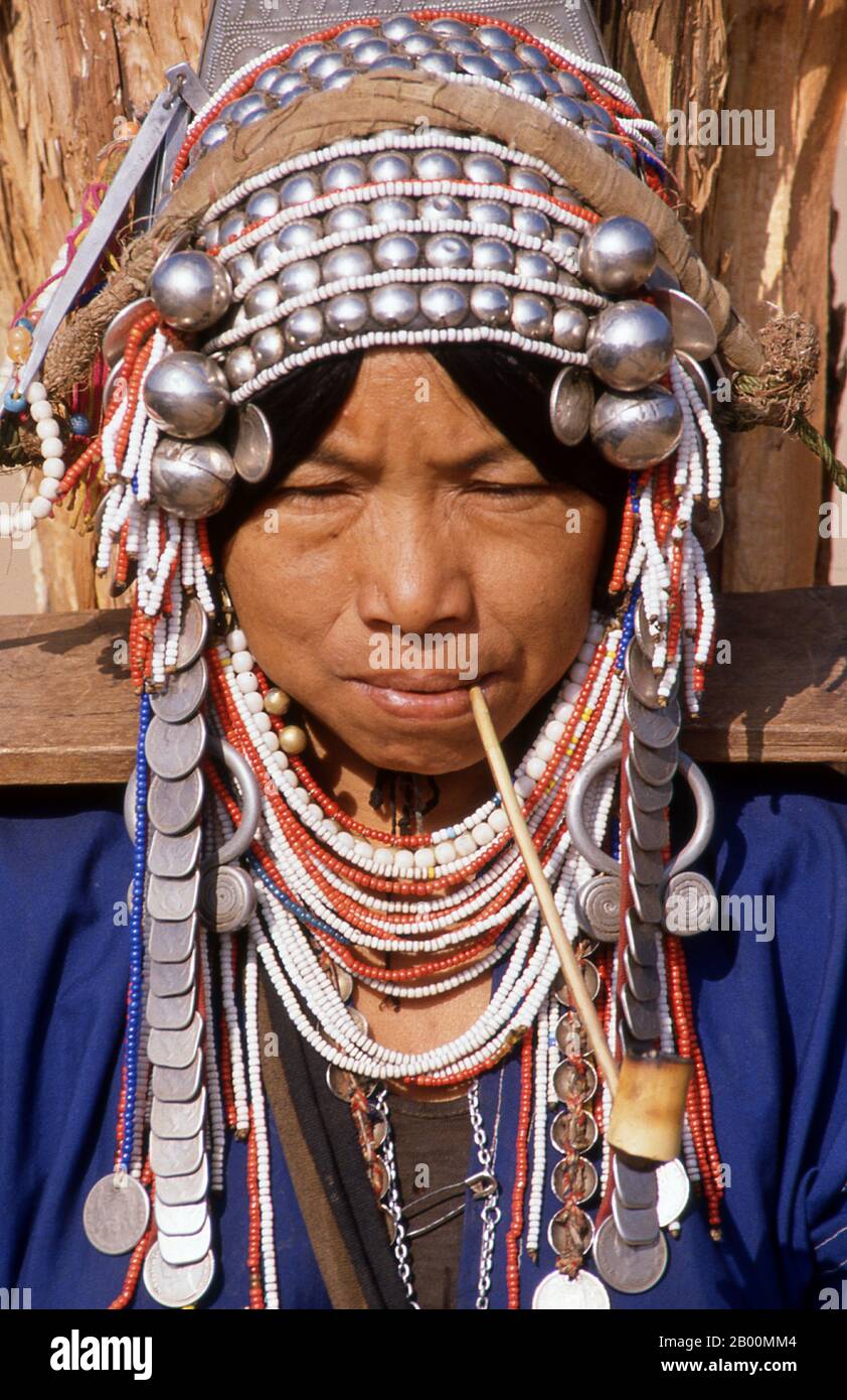Thailandia: Donna Akha fumante pipe, mercato di Doi Mae Salong (Santikhiri) mattina presto, provincia di Chiang Rai. Gli Akha sono una tribù collinare di contadini di sussistenza noti per la loro arte. Il gruppo etnico potrebbe essere originario della Mongolia circa 1500 anni fa. La maggior parte delle persone Akha rimanenti sono ora distribuite in piccoli villaggi tra le montagne della Cina, del Laos, del Myanmar (Birmania) e della Thailandia settentrionale, dove sono una delle sei principali tribù di colline. Gli Akha iniziarono ad arrivare in Thailandia all'inizio del ventesimo secolo e continuarono ad emigrare, con circa 80,000 abitanti che ora vivono in Thailandia. Foto Stock