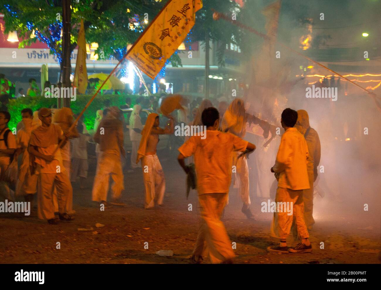 Thailandia: Le strade della città di Phuket esplodendo con i vigili del fuoco come la sfilata passa, Phuket Vegetarian Festival. Il Festival vegetariano è un festival religioso che si tiene ogni anno sull'isola di Phuket, nel sud della Thailandia. Attrae folle di spettatori a causa di molti degli insoliti rituali religiosi che vengono eseguiti. Molti devoti religiosi si schianteranno di spade, perforeranno le loro guance con oggetti taglienti e commetteranno altri atti dolorosi. Foto Stock