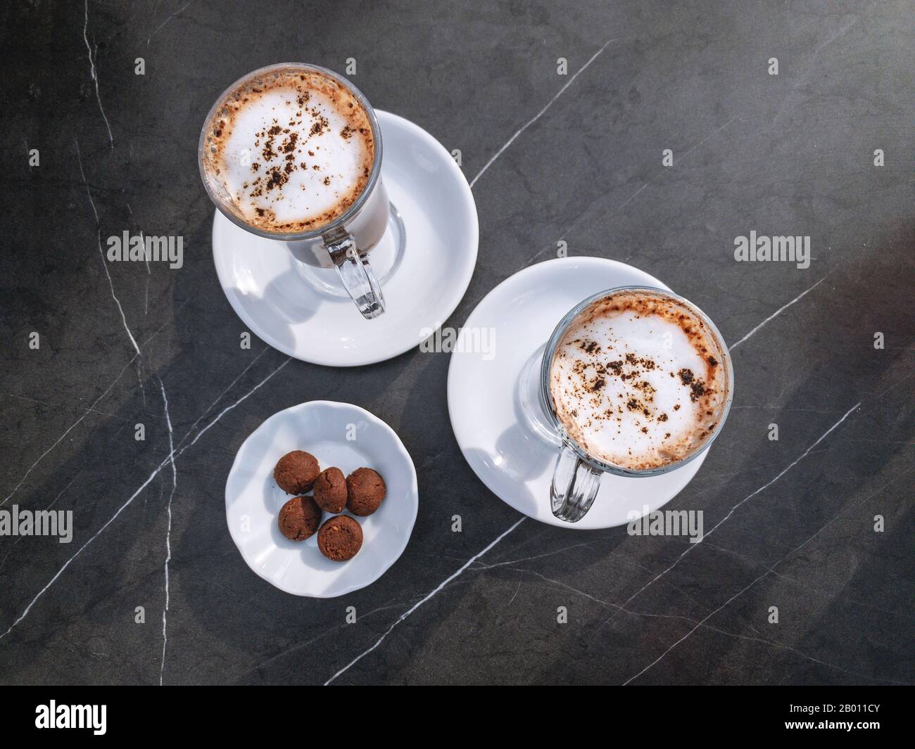 Due tazze di latte con schiuma e polvere di cioccolato pronti per il servis in un caffè Foto Stock