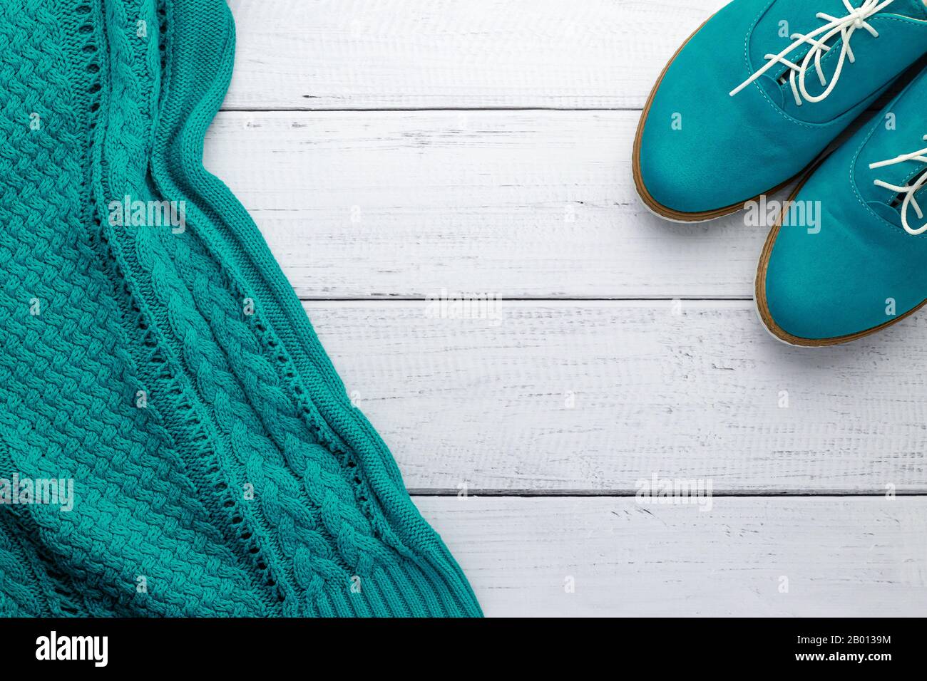 Maglia in maglia color acqua e camoscio verde scarpe oxford su sfondo di legno. Concetto femminile di stile autunnale, disposizione piatta di moda, vista dall'alto. Vintage donne Foto Stock