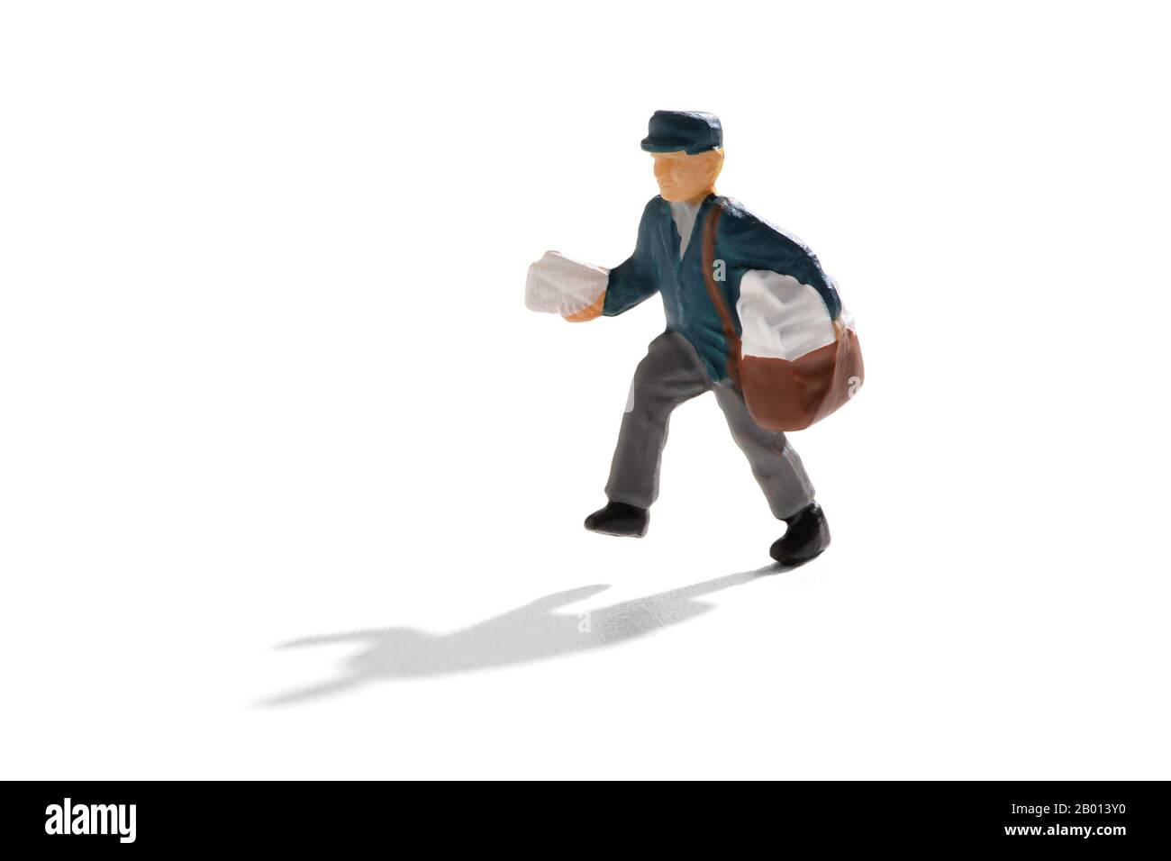 Mailman con una borsa che consegna lettere miniaturizzate, isolato su sfondo bianco con ombra Foto Stock