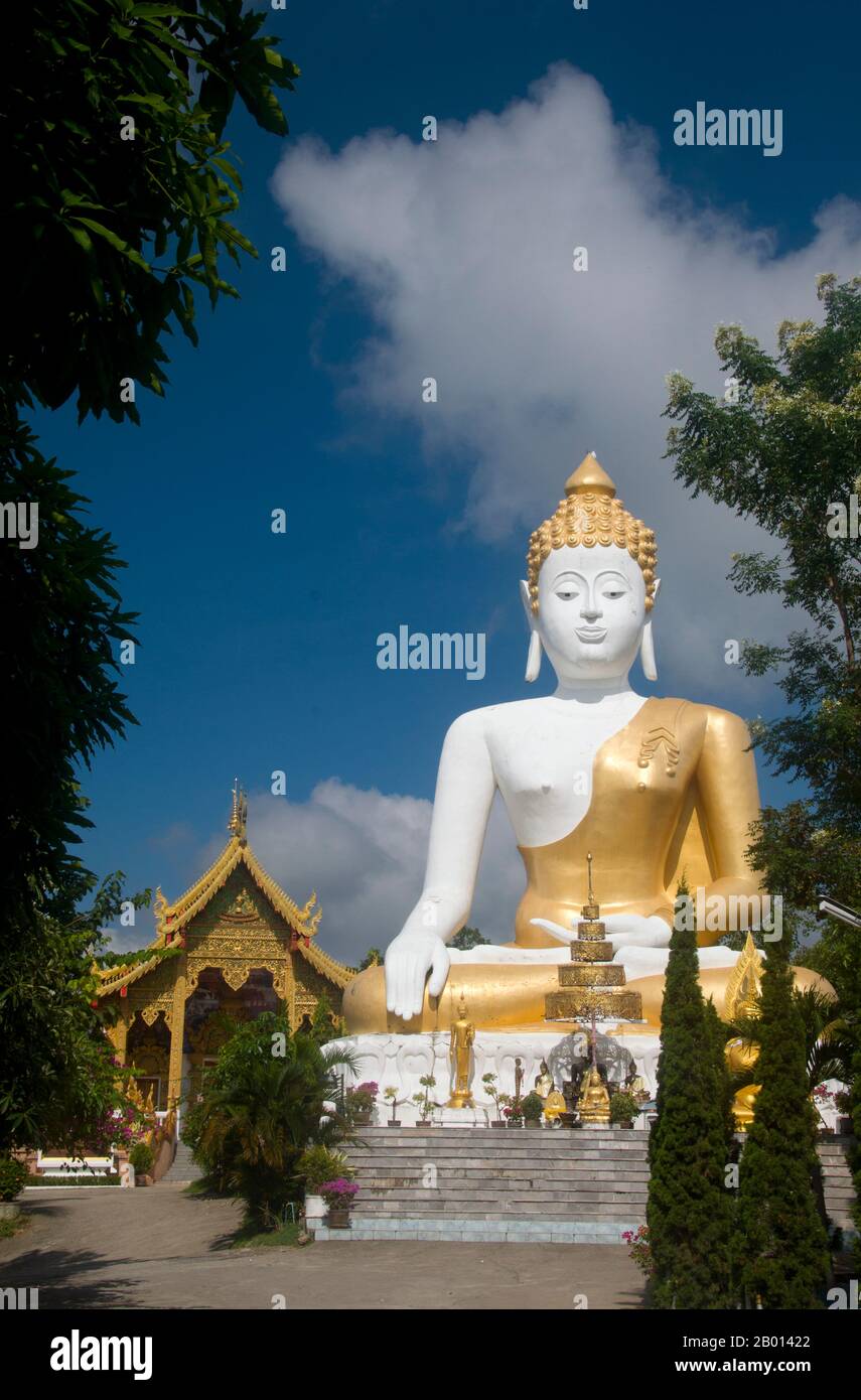 Thailandia: Statua di Buddha gigante che domina la valle di Chiang mai, Wat Phrathat Doi Kham, Chiang mai. Wat Phrathat Doi Kham o ‘Tempio del Monte d'Oro’, si trova a Tambon Mae HIA, a circa 10 km a sud della Città Vecchia di Chiang mai, nei rifugi di Doi Suthep. Il tempio registra che il tempio risale a oltre 1,300 anni ‘al 687 d.C.’, durante il periodo pre-LAN Na, quando la regione era abitata dall'animista indigeno Lawa. Chiang mai (che significa "nuova città"), talvolta scritta come "Chiengmai" o "Chiangmai", è la città più grande e culturalmente significativa della Thailandia settentrionale. Foto Stock