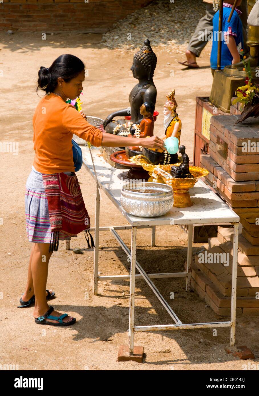 Thailandia: Una donna pulisce i Buddha con acqua a Wat Chetlin, Chiang mai, un rituale associato a songkran e ha creduto di portare buona fortuna nel prossimo anno. Songkran è il tradizionale Capodanno tailandese e si celebra dal 13 al 15 aprile. Questo festival annuale dell'acqua, conosciuto in tailandese come 'sonkran', e in birmano come 'thingyan' segna l'inizio della stagione delle piogge ed è celebrato in Birmania, Laos, Thailandia e altri paesi del sud-est asiatico, di solito in aprile. Foto Stock