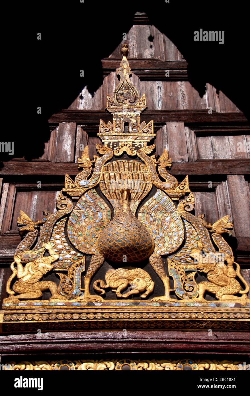 Thailandia: Il pavone di legno intagliato sopra l'ingresso principale, Wat Phan Tao, Chiang mai. Wat Phan Tao, fondata nel 1391, forma una sorta di aggiunta al molto più grande Wat Chedi Luang che si trova accanto e immediatamente a sud. Wat Phan Tao significa ‘Tempio di mille fornaci’ o ‘Tempio di mille forni’ e si ritiene che i terreni fossero un tempo il sito di una fonderia, gettando immagini in bronzo del Buddha per il vicino Wat Chedi Luang. Il viharn in legno è uno dei pochi edifici di tempio in legno sopravvissuti a Chiang mai. Foto Stock