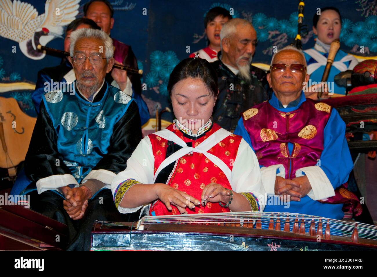 Cina: Una donna scopa un guzheng, la Naxi (Nakhi) Folk Orchestra, Naxi Orchestra Hall, Lijiang Old Town, Yunnan Province. La musica Naxi ha 500 anni e con la sua miscela di testi letterari, argomenti poetici e stili musicali delle dinastie Tang, Song e Yuan, così come alcune influenze tibetane, ha sviluppato il suo stile e i suoi tratti unici. Ci sono tre stili principali: Baisha, Dongjing e Huangjing, tutti utilizzando strumenti tradizionali cinesi. I Naxi o Nakhi sono un gruppo etnico che vive ai piedi delle colline dell'Himalaya nella parte nord-occidentale della provincia di Yunnan. Foto Stock