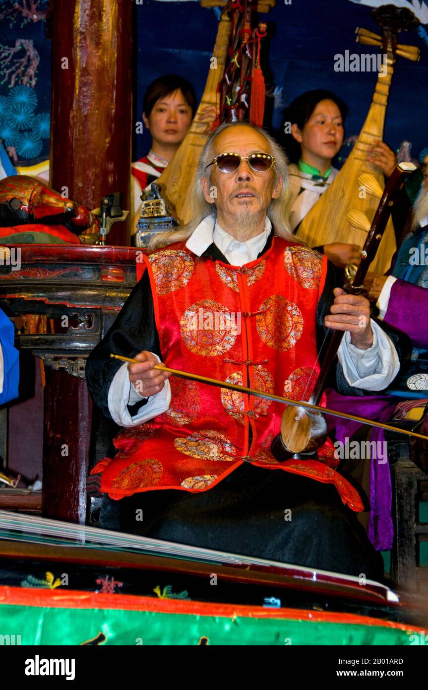 Cina: Un uomo suona un banhu, la Naxi (Nakhi) Folk Orchestra, Naxi Orchestra Hall, Lijiang Old Town, Yunnan Province. La musica Naxi ha 500 anni e con la sua miscela di testi letterari, argomenti poetici e stili musicali delle dinastie Tang, Song e Yuan, così come alcune influenze tibetane, ha sviluppato il suo stile e i suoi tratti unici. Ci sono tre stili principali: Baisha, Dongjing e Huangjing, tutti utilizzando strumenti tradizionali cinesi. I Naxi o Nakhi sono un gruppo etnico che vive ai piedi delle colline dell'Himalaya nella parte nord-occidentale della provincia di Yunnan. Foto Stock