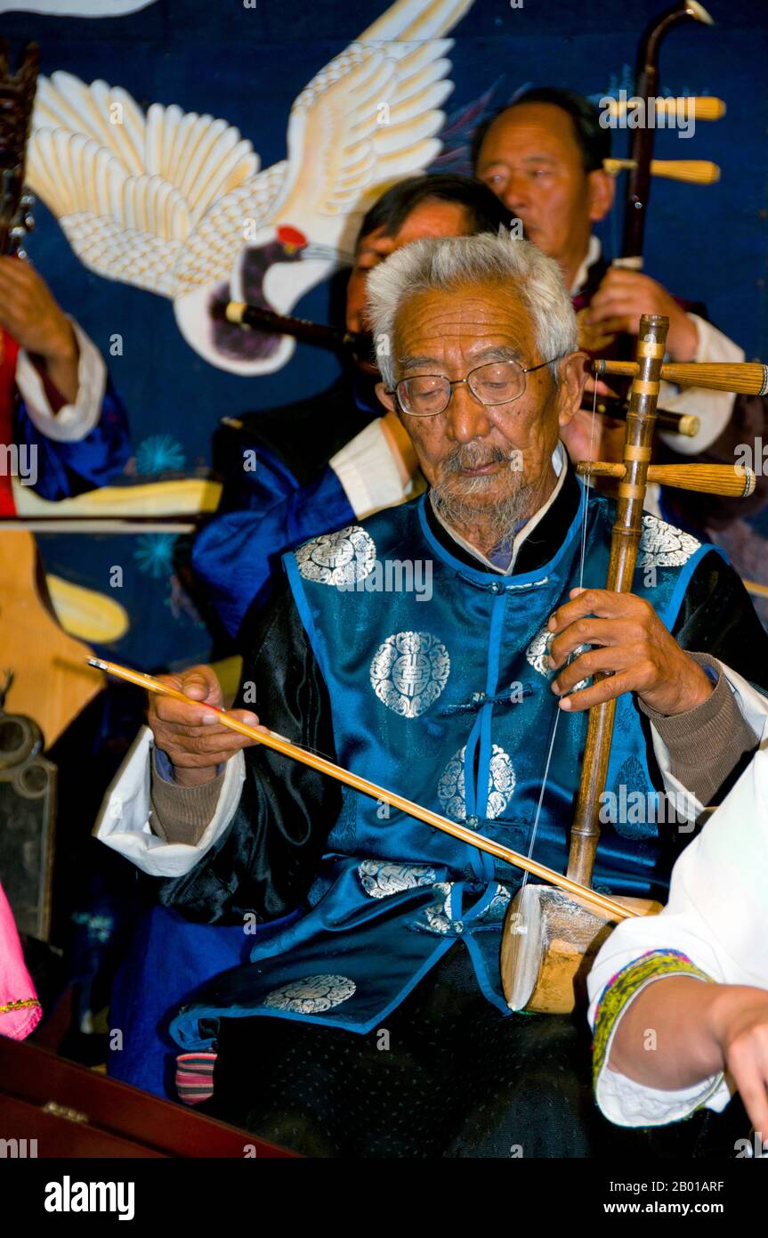 Cina: Un uomo suona un erhu, la Naxi (Nakhi) Folk Orchestra, Naxi Orchestra Hall, Lijiang Old Town, Yunnan Province. La musica Naxi ha 500 anni e con la sua miscela di testi letterari, argomenti poetici e stili musicali delle dinastie Tang, Song e Yuan, così come alcune influenze tibetane, ha sviluppato il suo stile e i suoi tratti unici. Ci sono tre stili principali: Baisha, Dongjing e Huangjing, tutti utilizzando strumenti tradizionali cinesi. I Naxi o Nakhi sono un gruppo etnico che vive ai piedi delle colline dell'Himalaya nella parte nord-occidentale della provincia di Yunnan. Foto Stock