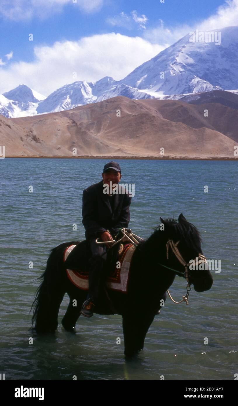 Cina: Kirghiz Horseman al Lago Karakul sulla Karakoram Highway, Xinjiang. Due piccoli insediamenti di nomadi Kirghiz (Kirghiz o Kirghiz) si trovano sul lato del lago Karakul in alto nelle montagne di Pamir. I visitatori possono pernottare in una delle loro case mobili o yurts – Kirghiz uomini si avvicineranno i viaggiatori come arrivare al lago e si offrono di organizzare questo alloggio. Il Kirghizistan è uno dei 56 gruppi etnici ufficialmente riconosciuti dalla Repubblica popolare cinese. In Cina ci sono più di 145.000 Kirghizistan. Foto Stock