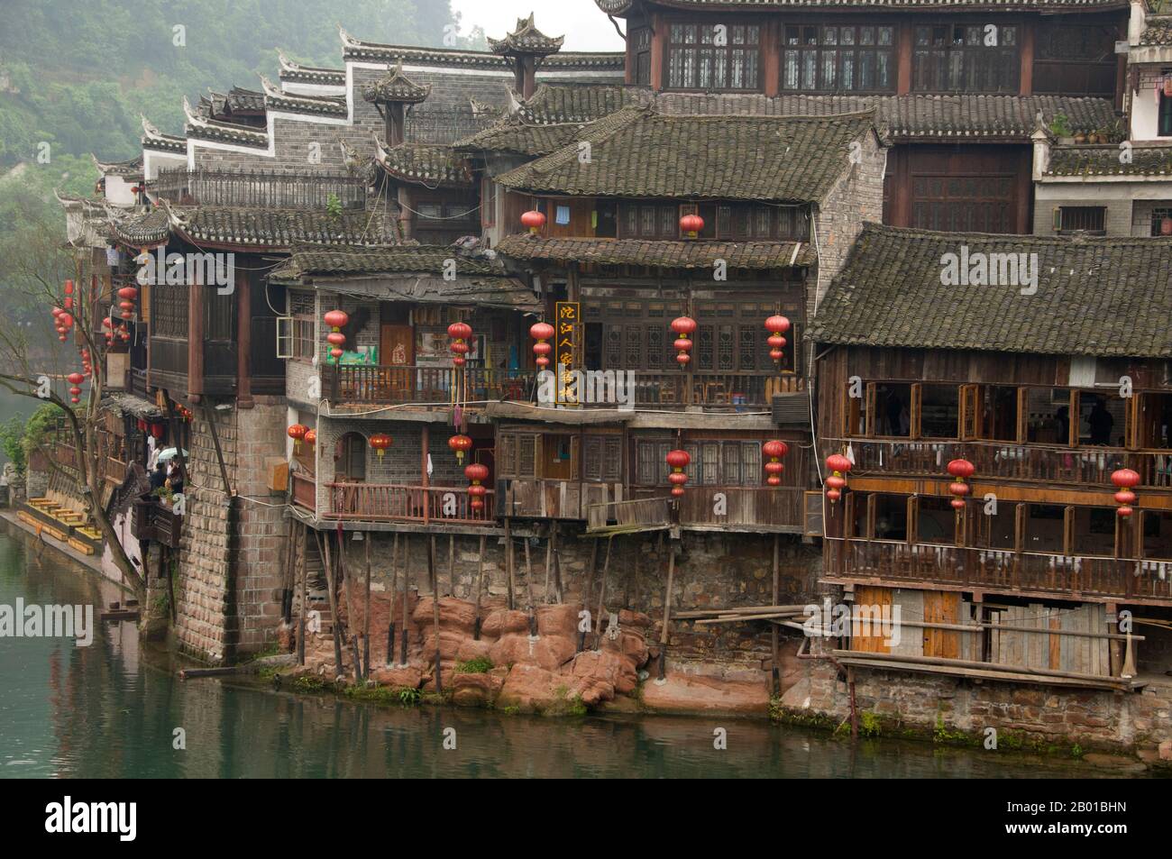 Cina: Vecchie case di legno lungo le rive del fiume Tuo, Fenghuang, provincia di Hunan. Fenghuang è cinese per Phoenix e si riferisce al mitico uccello da fuoco sacro che si può trovare nelle mitologie dei Persiani, Greci, Romani, Egiziani, Cinesi, E (secondo Sanchuniathon) i Fenici. La leggenda suggerisce che due phoenixes sulla scoperta della città hovered sopra per un certo tempo considerevole prima di volare riluttante via. Fenghuang è un'antica città ben conservata che risale al 248 a.C. Ospita le minoranze Miao e Tujia. Foto Stock