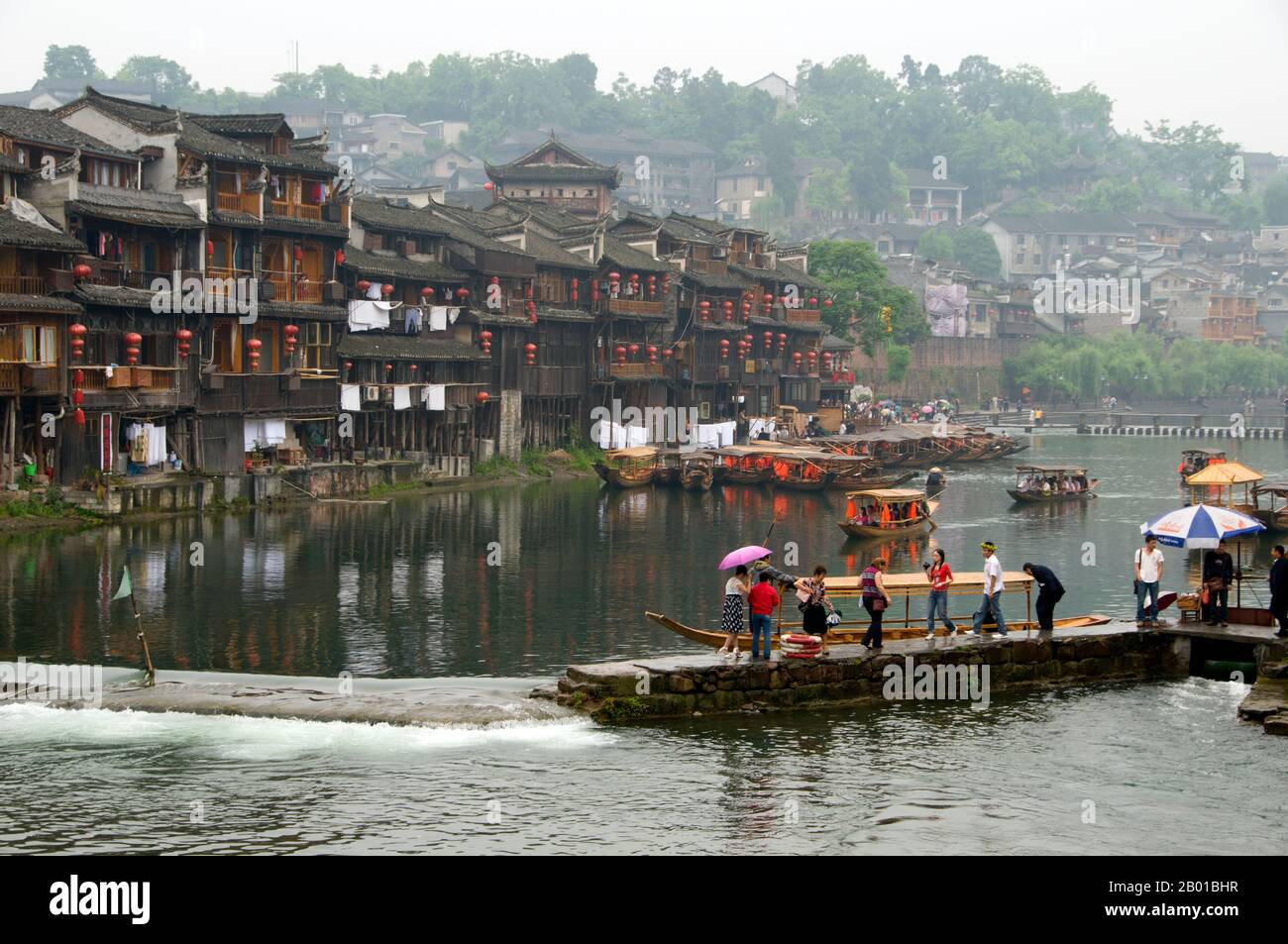 Cina: Vecchie case di legno lungo le rive del fiume Tuo, Fenghuang, provincia di Hunan. Fenghuang è cinese per Phoenix e si riferisce al mitico uccello da fuoco sacro che si può trovare nelle mitologie dei Persiani, Greci, Romani, Egiziani, Cinesi, E (secondo Sanchuniathon) i Fenici. La leggenda suggerisce che due phoenixes sulla scoperta della città hovered sopra per un certo tempo considerevole prima di volare riluttante via. Fenghuang è un'antica città ben conservata che risale al 248 a.C. Ospita le minoranze Miao e Tujia. Foto Stock