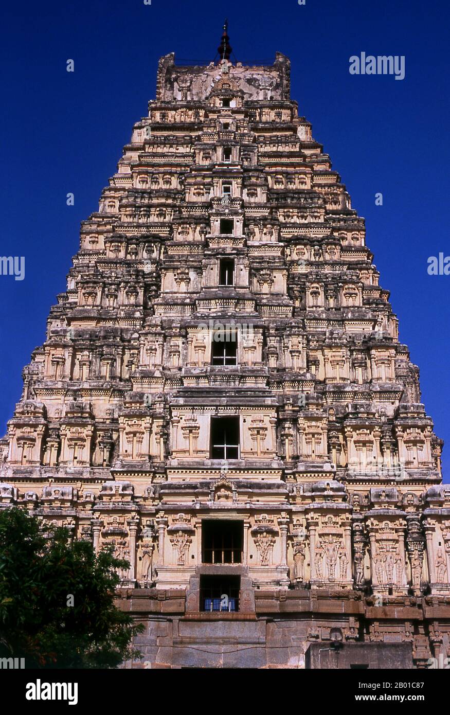 India: La torre orientale (gopuram) sorge sopra il tempio di Virupaksha, Hampi, stato di Karnataka. Il Tempio di Virupaksha (conosciuto anche come Tempio di Pampapathi) è il principale centro di pellegrinaggio di Hampi. E' completamente intatto tra le rovine circostanti ed è ancora utilizzato nel culto. Il tempio è dedicato al Signore Shiva, qui conosciuto come Virupaksha, come la consorte della dea locale Pampa, associata al fiume Tungabhadra. Hampi è un villaggio nel nord dello stato di Karnataka. Si trova all'interno delle rovine di Vijayanagara, l'ex capitale dell'Impero Vijayanagara. Foto Stock