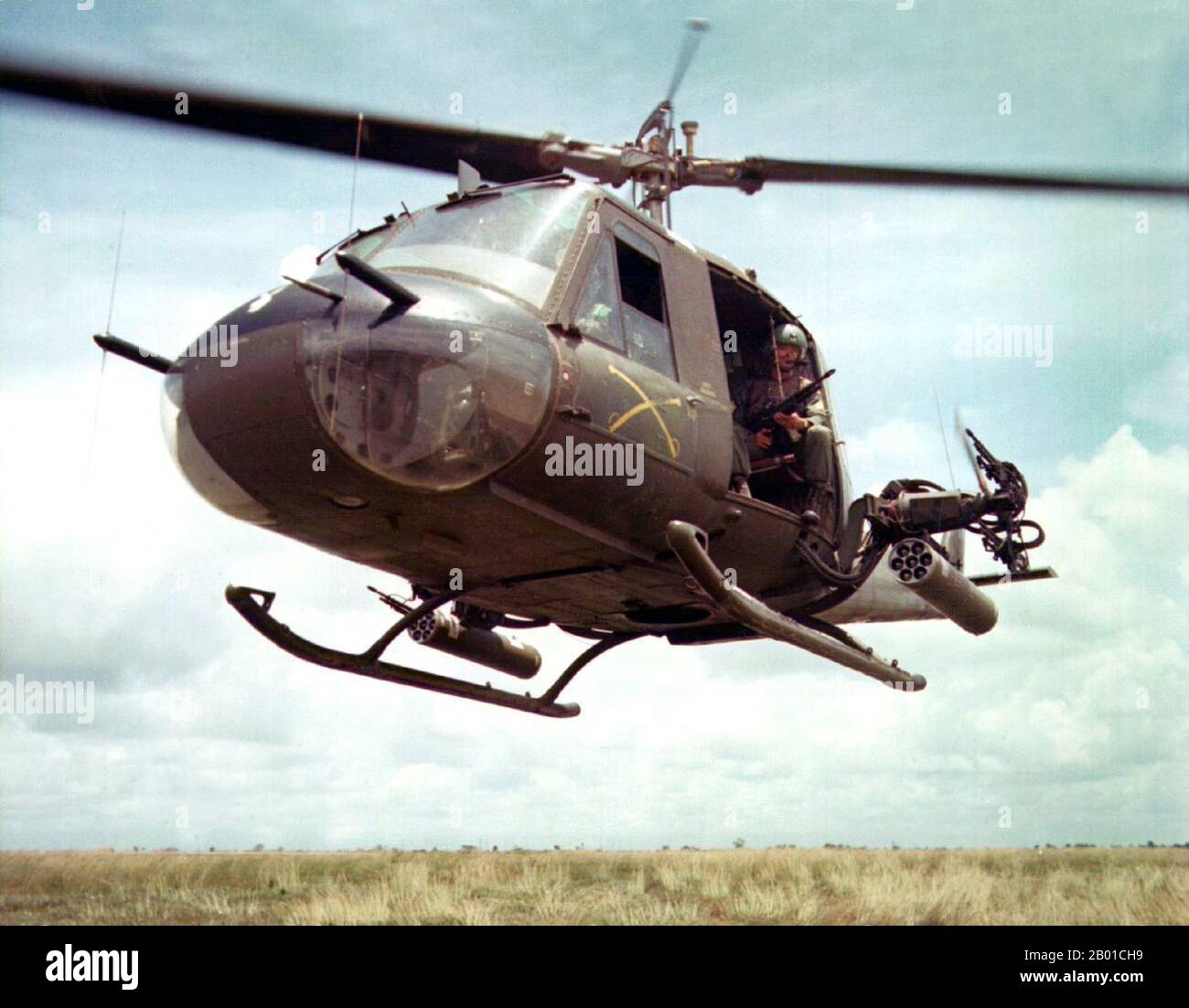 Vietnam: Stati Uniti Dennis Troxel siede come 'Shotgun Rider' nella porta di un elicottero Bell UH-1B Huey della 179th Aviation Company, Vietnam, 1965. La seconda guerra indochina, conosciuta in America come la guerra del Vietnam, fu un conflitto militare dell'epoca della guerra fredda che si verificò in Vietnam, Laos e Cambogia dal 1 novembre 1955 alla caduta di Saigon il 30 aprile 1975. Questa guerra seguì la prima Guerra d'Indocina e fu combattuta tra il Vietnam del Nord, sostenuto dai suoi alleati comunisti, e il governo del Vietnam del Sud, sostenuto dagli Stati Uniti e da altre nazioni anticomuniste. Foto Stock