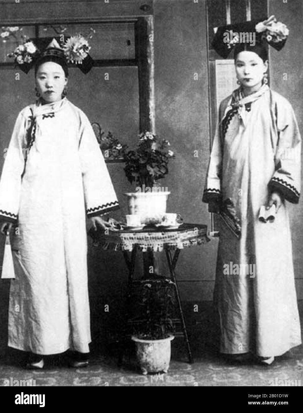 Cina: Signore di Manchu alla corte imperiale di Qing a Pechino, c. 1890. Le donne Manchu della Città Proibita o Gugong di Pechino posano per una fotografia durante la dinastia Manchu Qing (1644-1911). Indossano abiti elaborati e costosi. Le loro facce sono sbiancate con polvere, e il loro rossetto è applicato in una fascia stretta attraverso il centro delle loro labbra seguendo la moda del tempo. Foto Stock