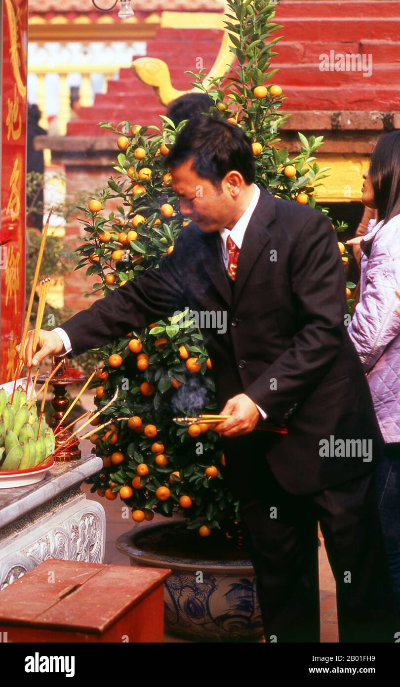 Vietnam: Tet (Capodanno vietnamita) celebranti a Tran Quoc Pagoda, ho Tay (Lago Ovest), Hanoi. Il tempio più antico di Hanoi, Chua Tran Quoc, si trova su una piccola isola appena ad ovest della strada sopraelevata di ho Tay. Le origini precise della pagoda sono sconosciute, ma secondo la leggenda fu originariamente fondata dalle rive del Fiume Rosso durante il regno di Re Ly Nam De (544-548) in un breve interregno durante il millennio dell’occupazione cinese. La più grande festa nazionale del Vietnam è Tet – più propriamente, Tet Nguyen Dan, “Festival del primo giorno” – in coincidenza con il primo giorno del capodanno lunare. Foto Stock