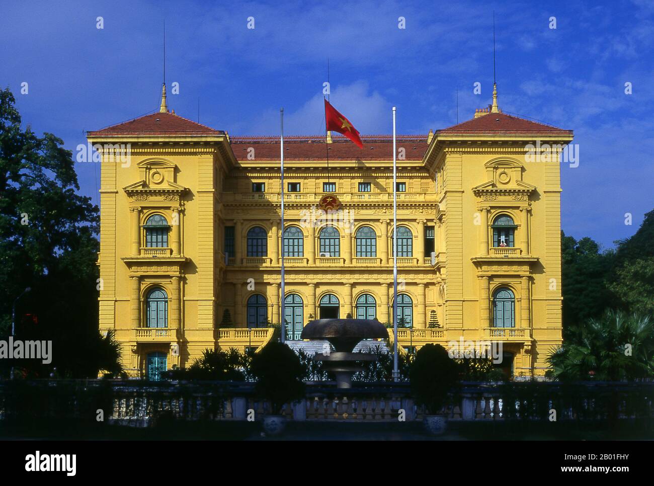 Vietnam: Il Palazzo Presidenziale, Hanoi. Il Palazzo Presidenziale fu originariamente costruito nel 1901 per Paul Doumer, allora governatore dell'Indocina francese. Dipinta nella pietra giallo senape scuro con le finestre verdi e le persiane sfinestrate così favorite in Vietnam, è ora principalmente impiegato per ricevere dignitari e capi di stato in visita. L'eroe nazionale vietnamita, ho Chi Minh, che divenne presidente della Repubblica democratica del Vietnam nel 1954, rifiutò di vivere qui. Secondo il suo biografo Duiker: “Ha rifiutato un’offerta dei suoi colleghi di vivere nel Palazzo del Governatore Generale...” Foto Stock