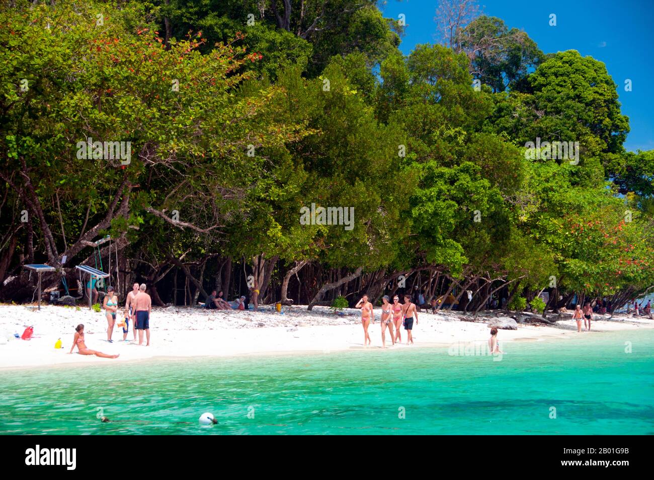 Thailandia: Un gruppo di tour si rilassa sulla spiaggia di Ko Rawi, Ko Tarutao Marine National Park. Ko Rawi è la seconda isola più grande del gruppo Adang-Rawi che fa parte a sua volta del Parco Nazionale Marino di Ko Tarutao. Ha una superficie di circa 29 kmq (11,5 kmq) e si trova a soli 10km km (6 miglia) ad ovest di Ko Adang. Il Parco Nazionale Marino di Ko Tarutao consiste di 51 isole in due gruppi principali sparsi attraverso il Mare delle Andamane nella Thailandia più meridionale. Solo sette delle isole sono di qualsiasi dimensione, tra cui Ko Tarutao a est, e Ko Adang-Ko Rawi a ovest. Foto Stock