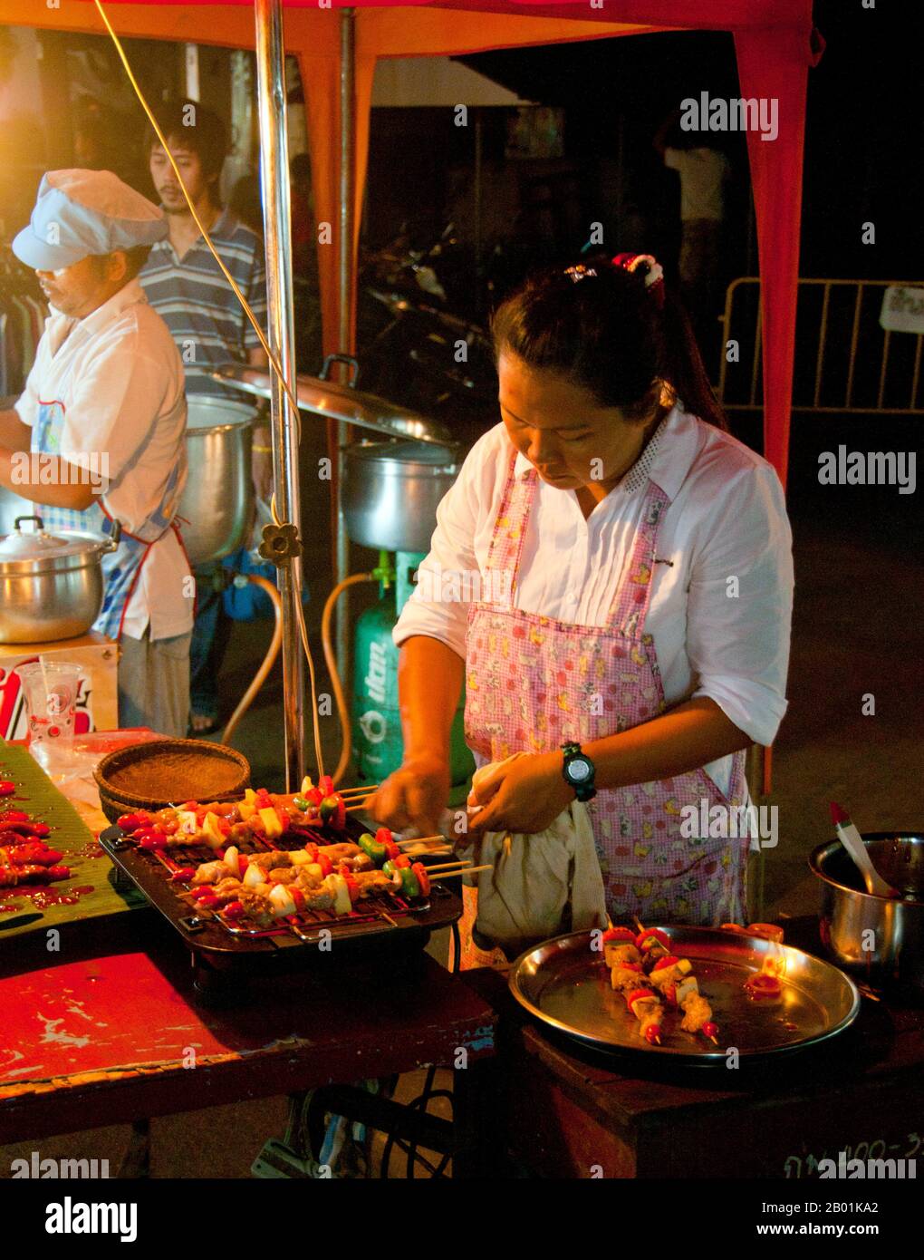 Thailandia: Venditore di kebab al mercato domenicale accanto alla stazione ferroviaria, Trang Town, Trang Province, Thailandia meridionale. Trang è stato un centro commerciale almeno dal i secolo d.C. Crebbe fino alla prosperità tra il VII e il XIII secolo durante il periodo Srivijaya e rimane oggi un'importante città commerciale. Gomma, olio di palma e pesca sono i pilastri dell'economia cittadina. Il turismo sta avendo un impatto crescente poiché la costa delle Andamane e le isole di Trang sono sempre più sviluppate e diffuse. Foto Stock