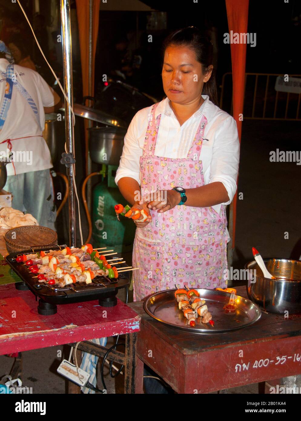 Thailandia: Venditore di kebab al mercato domenicale accanto alla stazione ferroviaria, Trang Town, Trang Province, Thailandia meridionale. Trang è stato un centro commerciale almeno dal i secolo d.C. Crebbe fino alla prosperità tra il VII e il XIII secolo durante il periodo Srivijaya e rimane oggi un'importante città commerciale. Gomma, olio di palma e pesca sono i pilastri dell'economia cittadina. Il turismo sta avendo un impatto crescente poiché la costa delle Andamane e le isole di Trang sono sempre più sviluppate e diffuse. Foto Stock