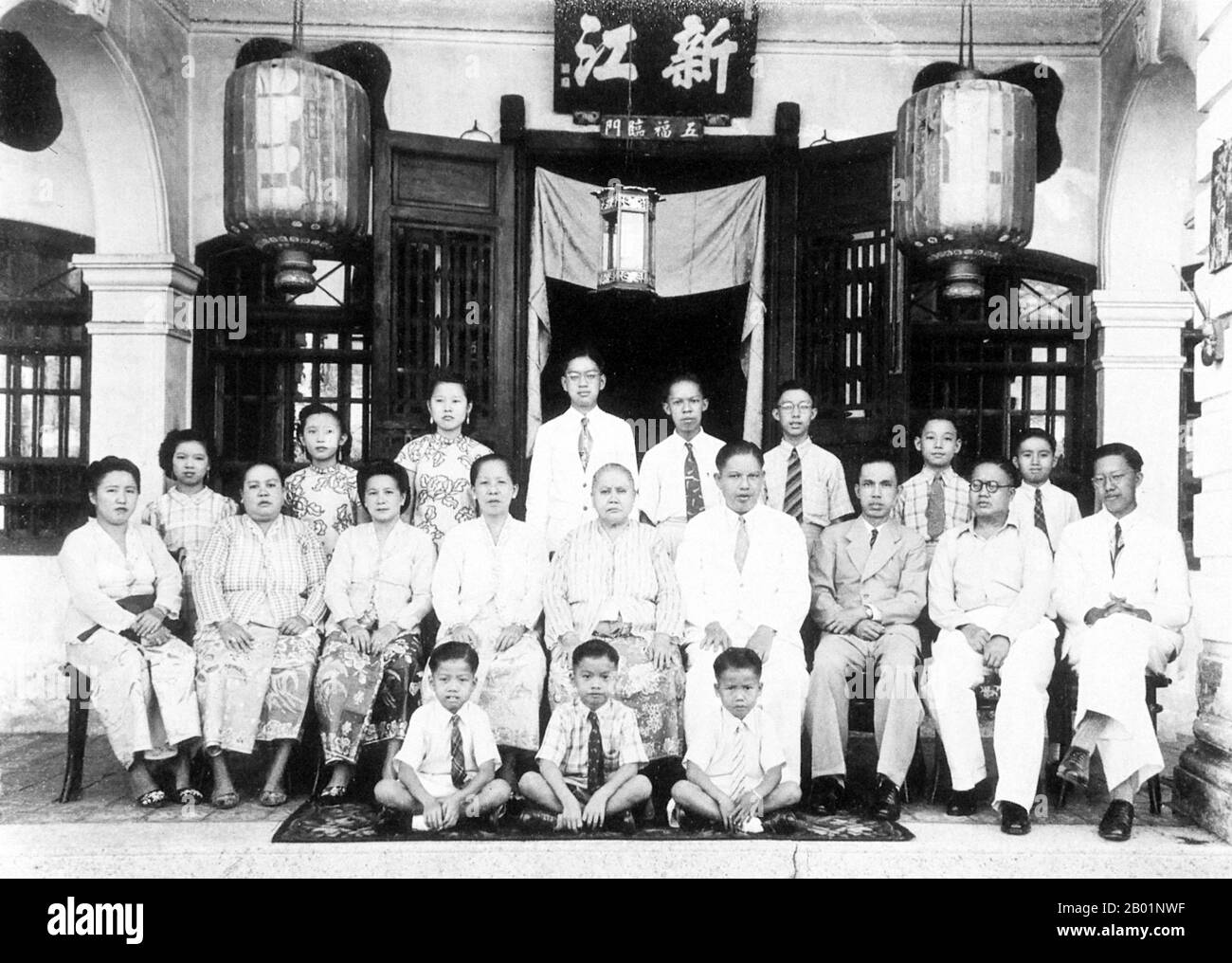 Malesia/Singapore: Una famiglia Peranakan allargata che si posa davanti alla loro bottega, all'inizio del XX secolo. Peranakan Chinese e Baba-Nyonya sono termini usati per indicare i discendenti degli immigrati cinesi della fine del XV e XVI secolo nell'arcipelago malese-indonesiano di Nusantara durante l'era coloniale. I membri di questa comunità in Malesia si identificano come "Nyonya-Baba" o "Baba-Nyonya". Nyonya è il termine per le femmine e Baba per i maschi. Si applica in particolare alle popolazioni etniche cinesi degli insediamenti dello stretto britannico della Malesia e dell'isola di Giava controllata dagli olandesi. Foto Stock