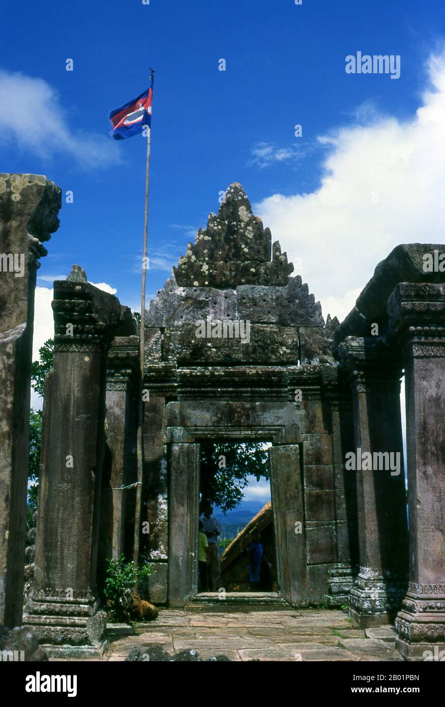 Cambogia: La bandiera cambogiana vola in cima a un gopura (ingresso) a Preah Vihear, un antico tempio Khmer al confine con la Thailandia. Adagiato su una scogliera al limitare dei Monti Dongrak, affacciato sulla Cambogia, Preah Vihear (conosciuta ai thailandesi come Khao Phra Viharn) è notevole sia per la sua eccezionale architettura Khmer che per la sua posizione mozzafiato. A lungo rivendicato sia dalla Thailandia che dalla Cambogia, il complesso del tempio fu infine assegnato a quest'ultimo dalla Corte Mondiale nel 1963, anche se la questione della proprietà irradia ancora molti thailandesi. Preah Vihear ha impiegato circa 200 anni per costruire. Foto Stock