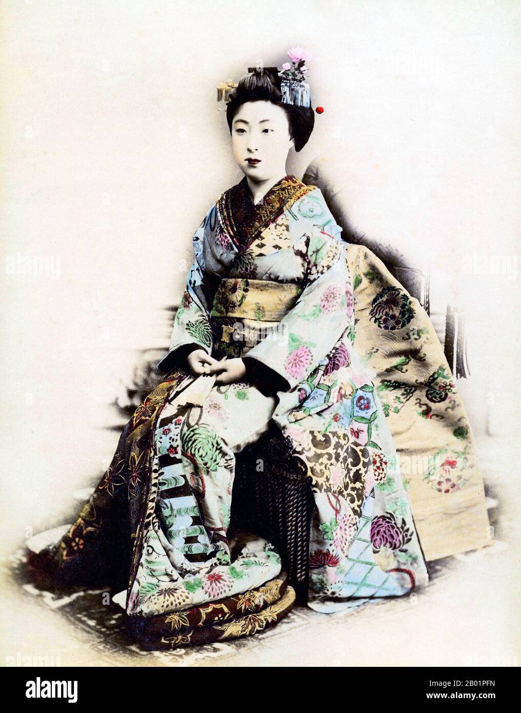 Giappone: Ritratto colorato a mano di una maiko in abito cerimoniale completo. Foto dallo studio Narui Raisuke (1858-1902), Kyoto, c. 1880. Maiko (舞妓?) è una parola giapponese che indica una ragazza danzante e significa un apprendista geisha. Di solito tra i 17 e i 20 anni, il loro lavoro consiste nell'eseguire canzoni, balli e suonare lo shamisen o altri strumenti tradizionali giapponesi per i visitatori durante banchetti e feste, noti come ozashiki. Si diplomano allo status di geisha dopo un periodo di formazione, e l'apprendistato può durare da pochi mesi a due anni. Sono noti come hangyoku (半玉) a Tokyo. Foto Stock