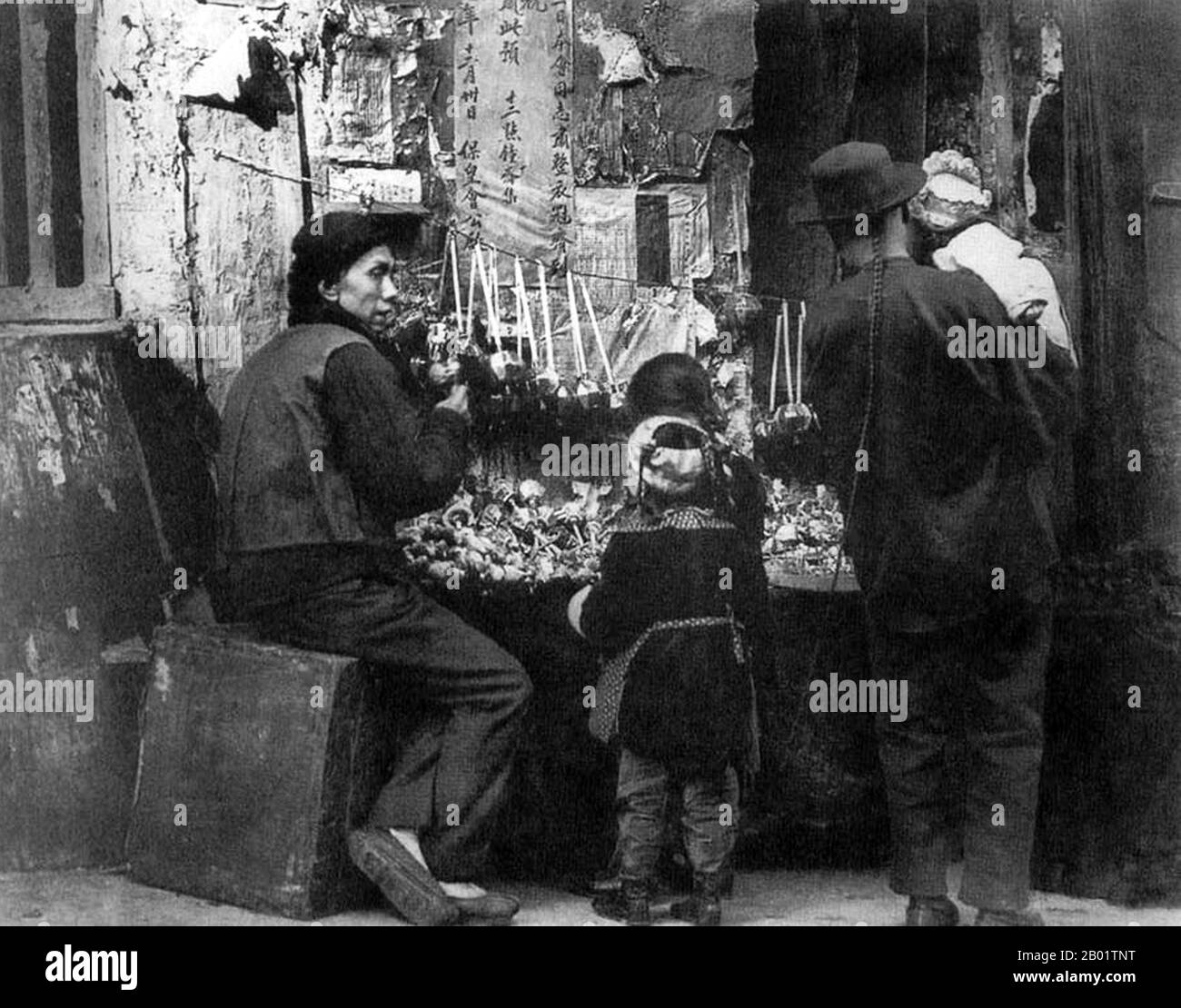 USA: Uomo cinese con coda e tre bambini in una stalla di giocattoli a lato della strada, San Francisco Chinatown. Foto di Arnold Genthe, c. 1900. Chinatown di San Francisco fu il porto di ingresso per i primi immigrati cinesi hoisanese e Zhongshanese dalla provincia del Guangdong della Cina meridionale dagli anni '1850 agli anni '1900 L'area era l'unica regione geografica detenuta dal governo cittadino e dai proprietari di proprietà private che permettevano ai cinesi di ereditare e abitare abitazioni all'interno della città. La maggior parte di questi negozianti cinesi, proprietari di ristoranti e lavoratori assunti a San Francisco erano hoisanesi Foto Stock