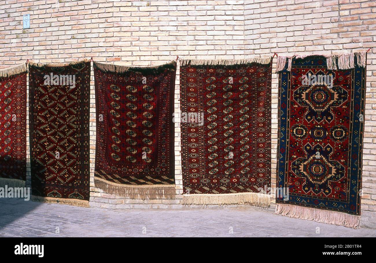 Uzbekistan: Mostra di tappeti al Taqi Telpak Furushon (i produttori di berretti) Bazaar, Bukhara. Bukhara fu fondata nel 500 a.C. nell'area ora chiamata Arca. Tuttavia, l'oasi di Bukhara era stata abitata molto prima. La città è stata uno dei principali centri della civiltà persiana fin dai suoi primi giorni nel vi secolo a.C. A partire dal vi secolo, i parlanti turchi si spostarono gradualmente. L'architettura e i siti archeologici di Bukhara formano uno dei pilastri della storia e dell'arte dell'Asia centrale. La regione di Bukhara fu per un lungo periodo parte dell'Impero persiano. Foto Stock