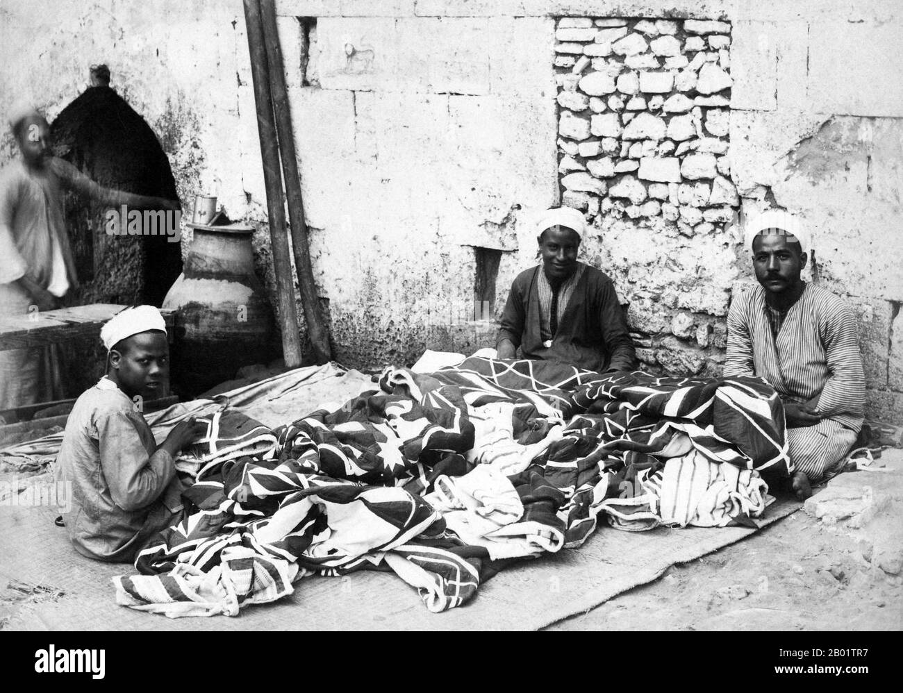 Egitto: Produttori di tappeti al Cairo. Foto degli Adelphoi Zangaki/Zangaki Brothers, fine XIX secolo. Un autentico tappeto orientale è un tappeto fatto a mano che è annodato con un pelo o intrecciato senza pelo. Per definizione - i tappeti orientali sono tappeti che provengono dall'Oriente. La semplice definizione del termine sarebbe - tappeti che provengono (sono stati fatti in) da un paese asiatico come: Cina e Vietnam ad est alla Turchia, paesi del Maghreb, Cipro e Iran ad ovest e il Caucaso a nord fino all'India a sud. Foto Stock