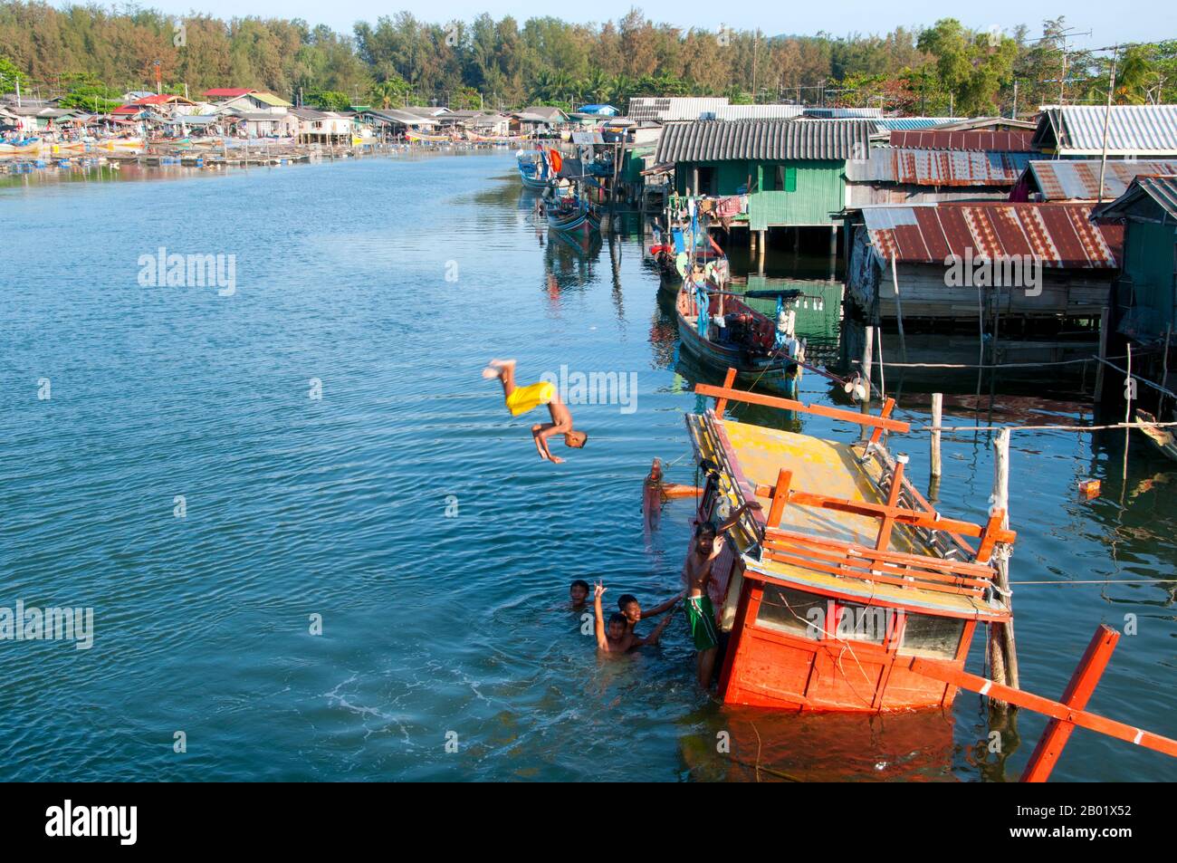 Thailandia: Ragazzi che si tuffano da una barca da pesca sommersa, Narathiwat, Thailandia meridionale. Narathiwat è uno dei pochi punti in cui il mondo tailandese e quello malese si incontrano e si mescolano con quello dei cinesi d'oltremare. Ciò ha portato a un sistema sociale intrigante e complesso, in cui i buddisti di lingua thailandese controllano la burocrazia, i cinesi etnici gestiscono l'economia urbana e i musulmani di lingua malese coltivano la campagna e pescano i mari. Narathiwat è una cittadina tranquilla e appartata di circa 40.000 persone - una delle più piccole capitali provinciali della Thailandia - con un carattere tutto suo. Foto Stock