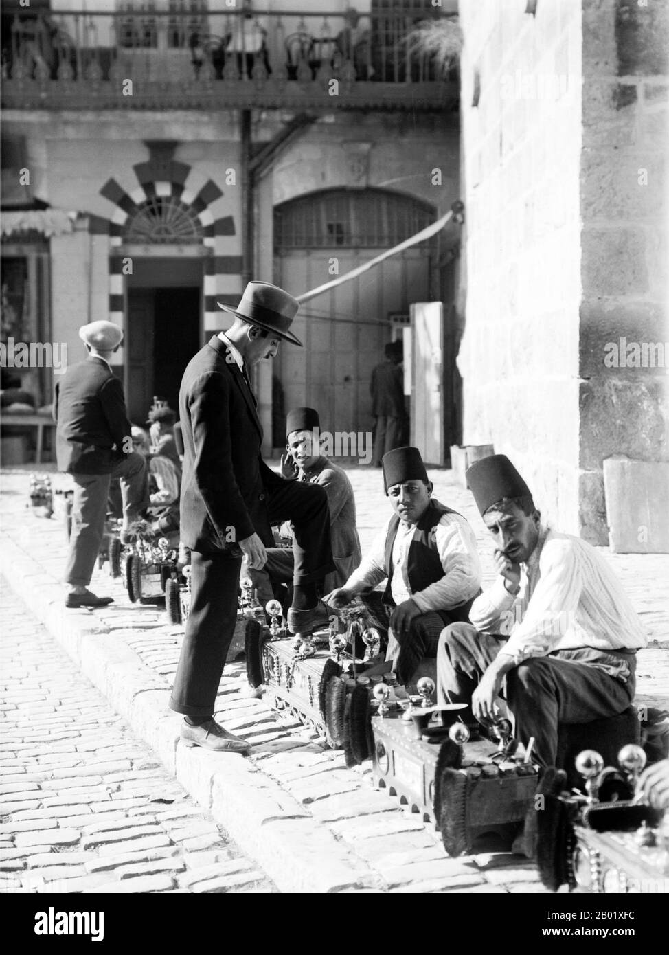 Palestina: Shoeshiners at the Jaffa Gate, Gerusalemme, 1920 circa. Palestina è un nome dato alla regione geografica tra il Mar Mediterraneo e il fiume Giordano. La regione è anche conosciuta come la Terra di Israele, la Terra Santa e il Levante meridionale. Nel 1832 la Palestina fu conquistata dall'Egitto di Muhammad Ali, ma nel 1840 la Gran Bretagna intervenne e restituì il controllo del Levante agli ottomani in cambio di ulteriori capitolazioni. La fine del XIX secolo vide l'inizio dell'immigrazione sionista e la rinascita della lingua ebraica. Foto Stock