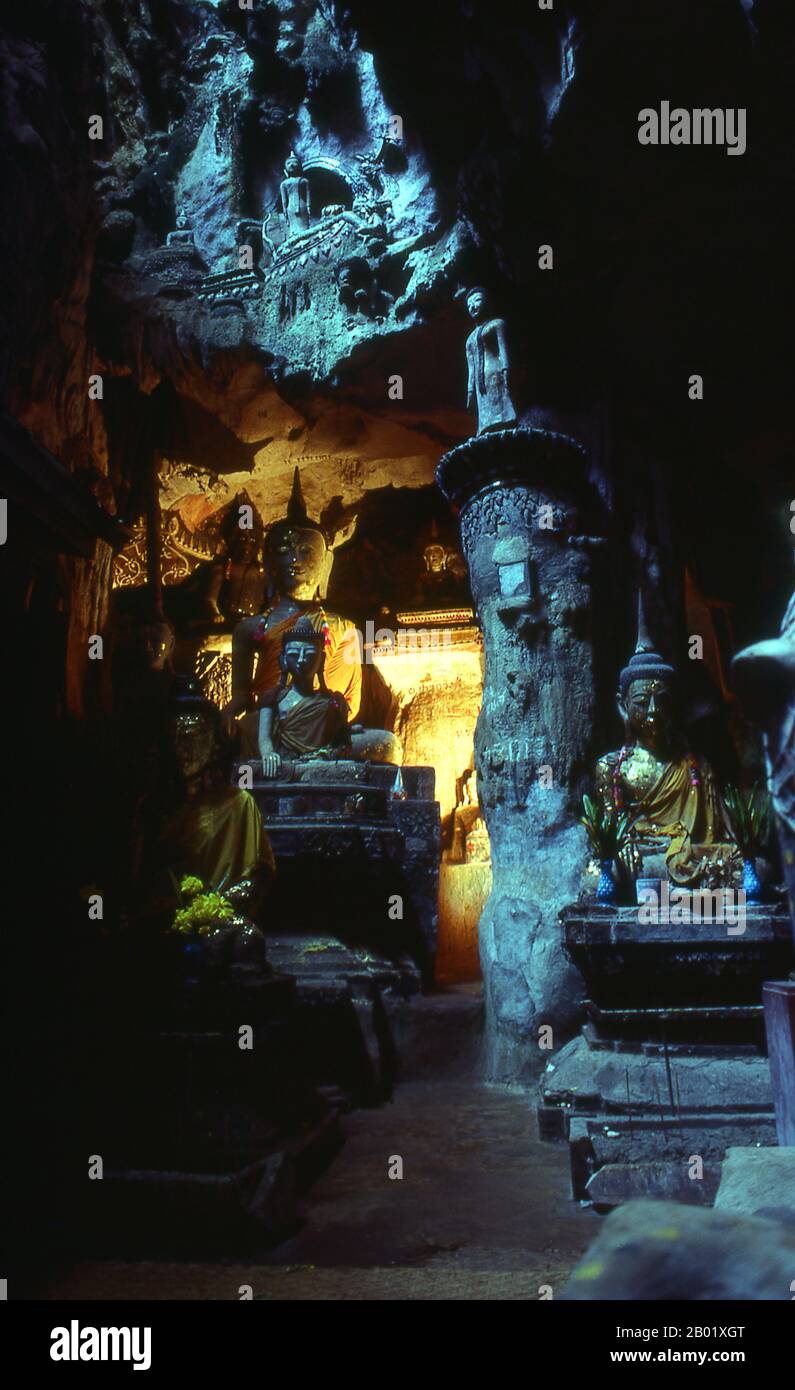 Thailandia: Un raggio di luce solare illumina le figure di Buddha raccolte all'interno delle grotte di Doi Chiang Dao (montagna di Chiang Dao), Chiang Dao, Thailandia settentrionale. Situato a 70 chilometri a nord di Chiang mai (Thailandia settentrionale) sulla strada per Fang, Chiang Dao si trova al riparo sotto l'impressionante mole di Doi Chiang Dao, un massiccio affioramento di roccia che si innalza ripidamente sulla città fino a un'altezza di 2.175 metri. La vetta, la terza più alta della Thailandia, è di solito avvolta da nuvole ed è sede di numerosi villaggi delle tribù collinari, tra cui gli insediamenti di Lisu, Lahu e Karen. Foto Stock