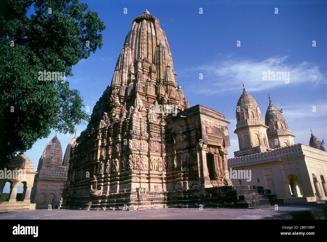 India: L'arcaico tempio di Parsvanath si trova vicino al nuovo tempio di Santinatha, Khajuraho, stato del Madhya Pradesh. Durante il X e l'XI secolo, i re Chandella dell'India centrale, le eredi di un potente clan Rajput che rivendicava la luna come loro antenato diretto, costruirono un totale di 85 templi per la gloria di Dio, la creazione e il pantheon indù. I Chandellas erano devoti indù. Eclissati dalla conquista moghul, dall'ascesa di dinastie rivali e dal passare del tempo, i templi languirono sotto il sole duro e le piogge monsoniche dell'India centrale, perdendo gradualmente nella giungla. Foto Stock