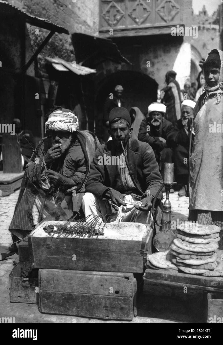 Palestina: Venditore palestinese di kebab e focaccia con clienti in un mercato di Gerusalemme, c. 1900-1920. Palestina è un nome dato alla regione geografica tra il Mar Mediterraneo e il fiume Giordano. La regione è anche conosciuta come la Terra di Israele, la Terra Santa e il Levante meridionale. Nel 1832 la Palestina fu conquistata dall'Egitto di Muhammad Ali, ma nel 1840 la Gran Bretagna intervenne e restituì il controllo del Levante agli ottomani in cambio di ulteriori capitolazioni. La fine del XIX secolo vide l'inizio dell'immigrazione sionista e la rinascita della lingua ebraica. Foto Stock