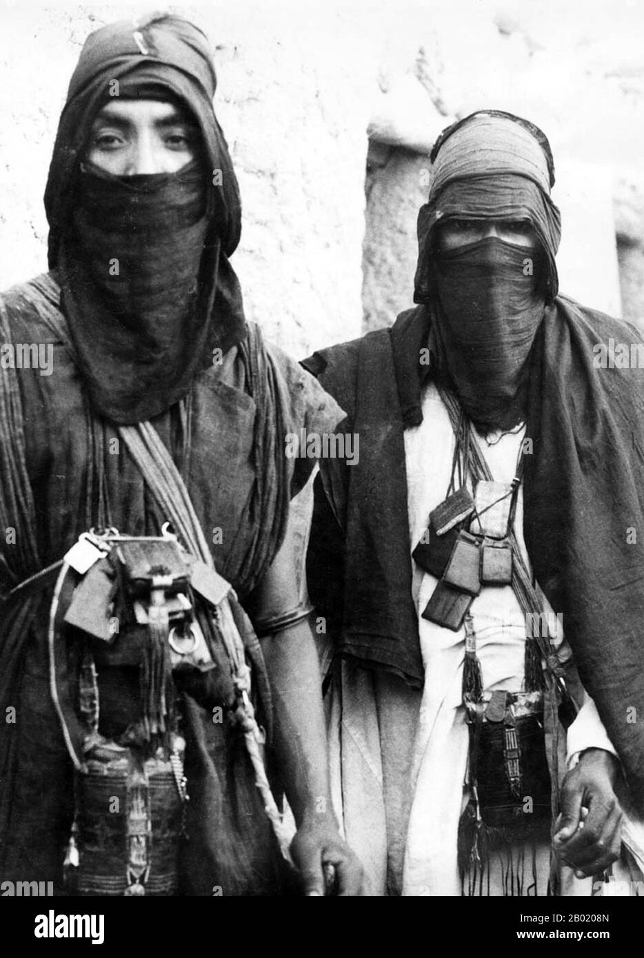 Arabia: Beduini uomini in abito tradizionale, c. 1920. I beduini fanno parte di un gruppo etnico arabo che abita prevalentemente nel deserto tradizionalmente diviso in tribù, o clan, conosciuti in arabo come ʿašāʾir. Il termine "beduino" deriva da una forma plurale della parola araba badawī, in quanto è pronunciata nei dialetti colloquiali. Il termine arabo badawī deriva dalla parola bādiyah, che significa deserto semiarido (al contrario di ṣaḥarāʾ che significa deserto). A partire dalla fine del XIX secolo, molti beduini sotto il dominio britannico iniziarono a transitare verso una vita seminomadica. Foto Stock