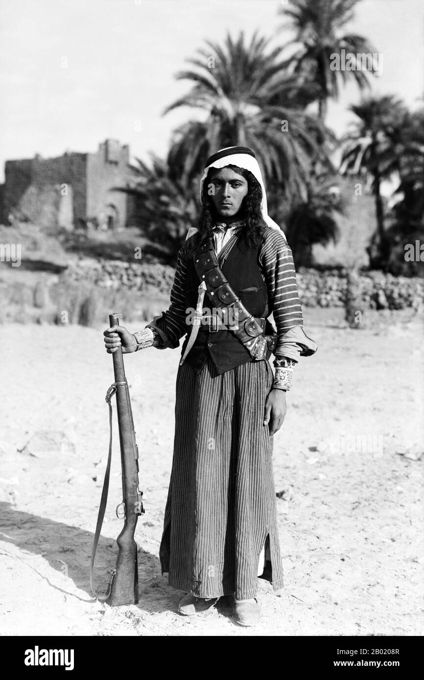Jordan: Un giovane beduino con il suo fucile, Qasr al-azraq, 1926 anni. I beduini fanno parte di un gruppo etnico arabo che abita prevalentemente nel deserto tradizionalmente diviso in tribù, o clan, conosciuti in arabo come ʿašāʾir. Il termine "beduino" deriva da una forma plurale della parola araba badawī, in quanto è pronunciata nei dialetti colloquiali. Il termine arabo badawī deriva dalla parola bādiyah, che significa deserto semiarido (al contrario di ṣaḥarāʾ che significa deserto). A partire dalla fine del XIX secolo, molti beduini sotto il dominio britannico iniziarono a transitare verso una vita seminomadica. Foto Stock Jordan: Un giovane beduino con il suo fucile, Qasr al-azraq, 1926 anni. I beduini fanno parte di un gruppo etnico arabo che abita prevalentemente nel deserto tradizionalmente diviso in tribù, o clan, conosciuti in arabo come ʿašāʾir. Il termine "beduino" deriva da una forma plurale della parola araba badawī, in quanto è pronunciata nei dialetti colloquiali. Il termine arabo badawī deriva dalla parola bādiyah, che significa deserto semiarido (al contrario di ṣaḥarāʾ che significa deserto). A partire dalla fine del XIX secolo, molti beduini sotto il dominio britannico iniziarono a transitare verso una vita seminomadica. Foto Stock